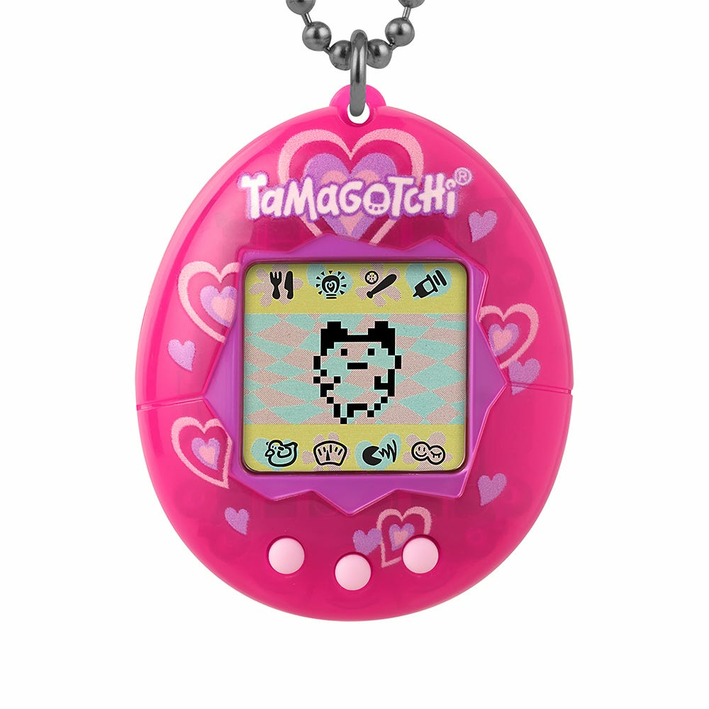 Różowy Tamagotchi z czarno-białym pikselowym zwierzakiem na ekranie, wiszący na łańcuszku.