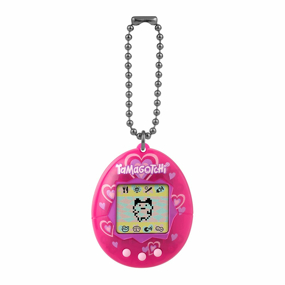 Różowy Tamagotchi z motywem serc, wiszący na łańcuszku. Ekran wyświetla pikselowego zwierzaka.