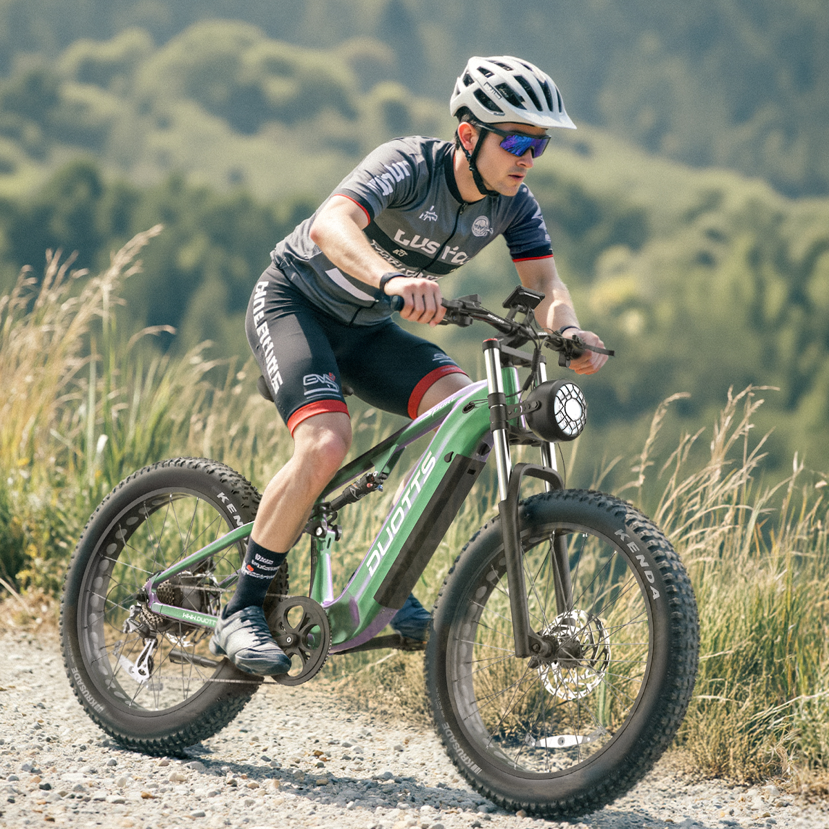 Mężczyzna na zielonym rowerze górskim, w kasku i okularach przeciwsłonecznych.