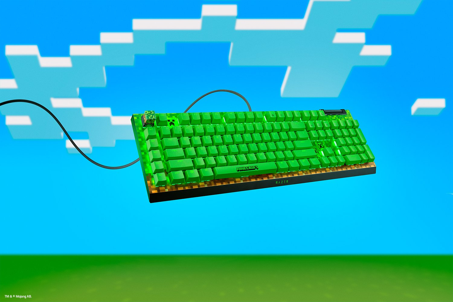 Klawiatura Razer Minecraft z zielonymi klawiszami na tle Minecraft z chmurami i trawą.