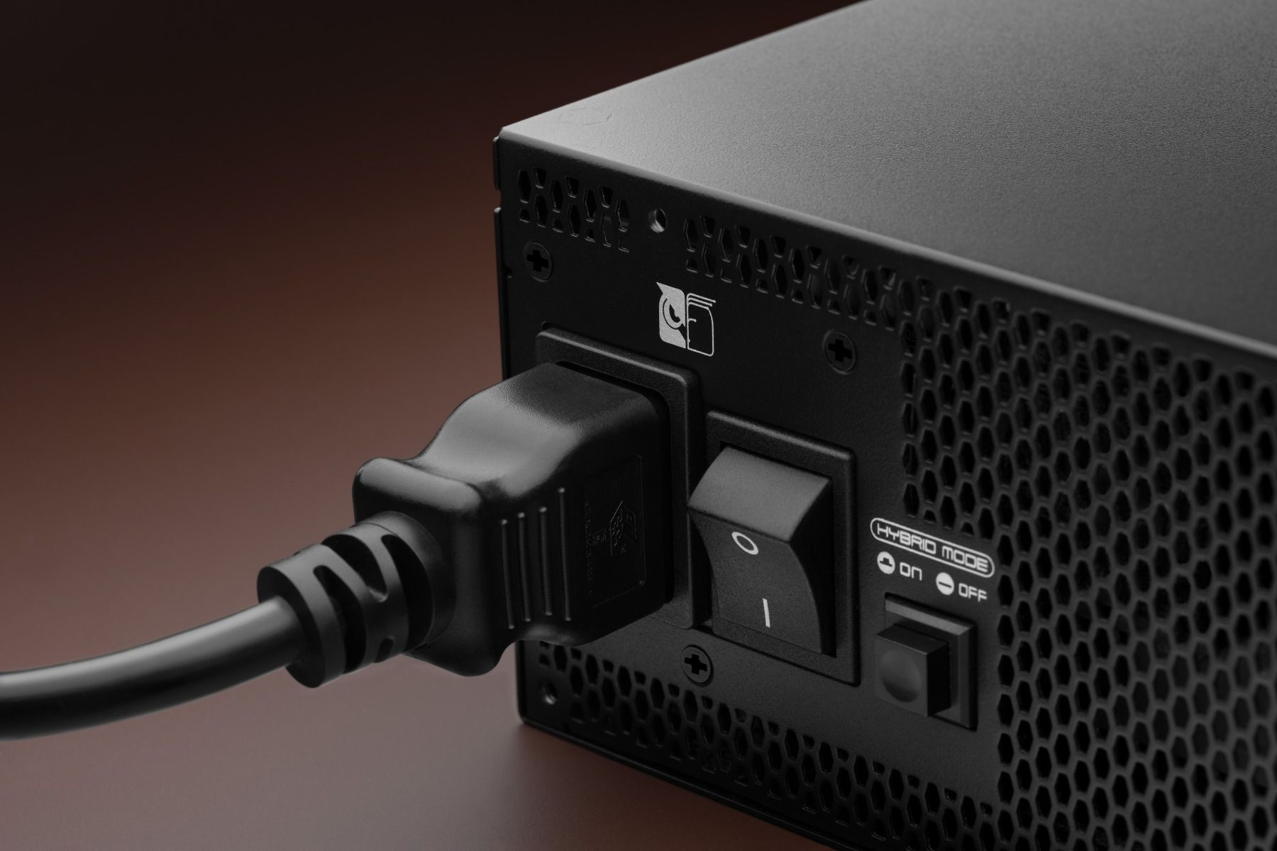 Alimentation noire avec cordon d'alimentation, interrupteur et mode hybride. Fond marron.