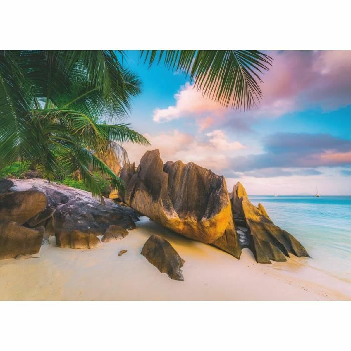 Scène de plage avec palmiers, grands rochers et eau et ciel bleus. Couleurs du coucher de soleil visibles.