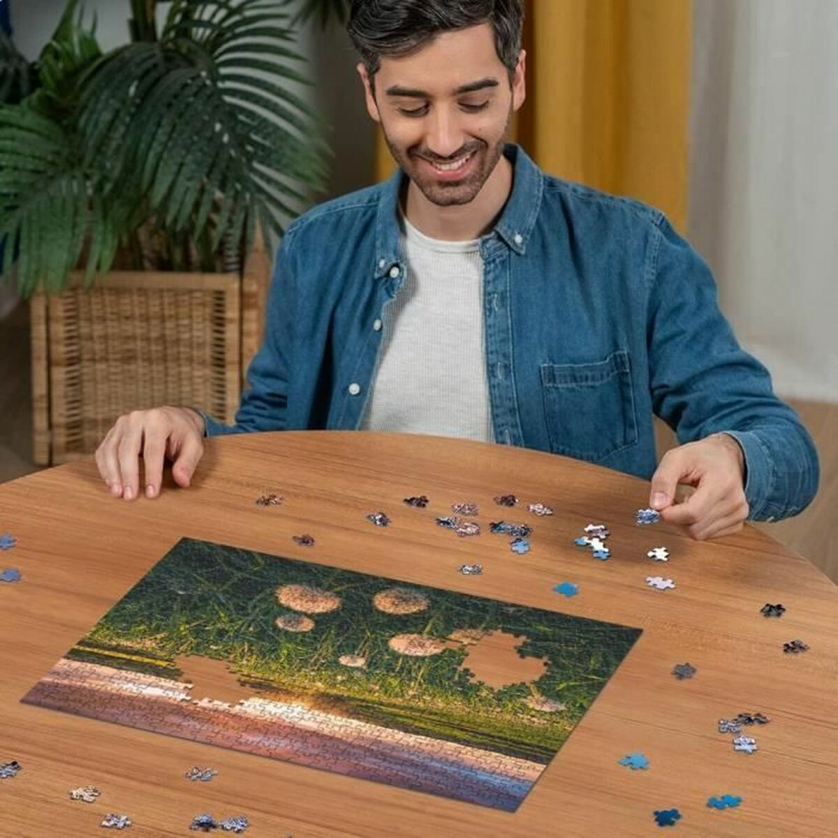 Ein Mann lächelt beim Puzzeln eines Naturmotives auf einem Holztisch.