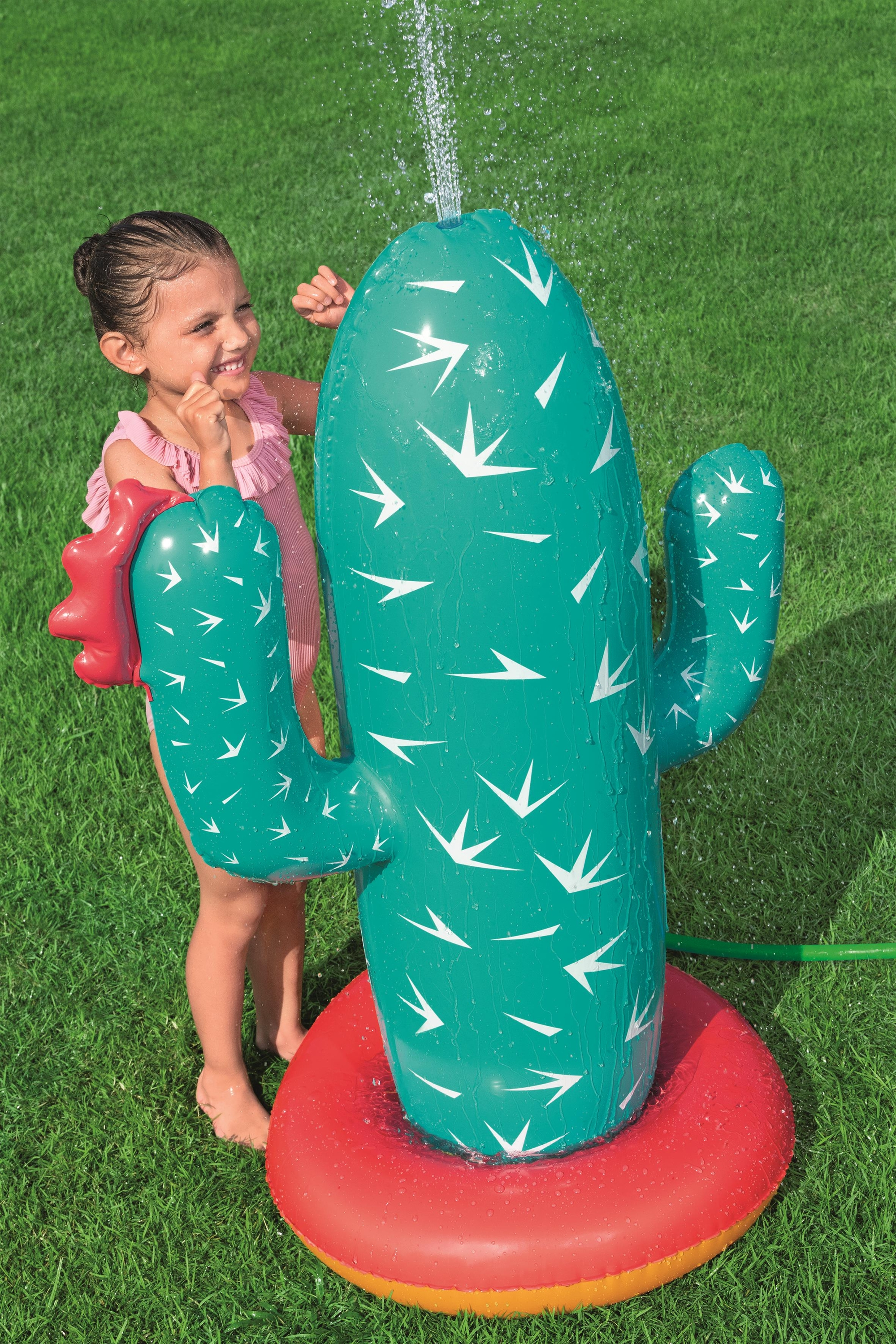Dziewczynka bawi się nadmuchiwanym kaktusem zraszającym wodą, z wodą tryskającą z góry.