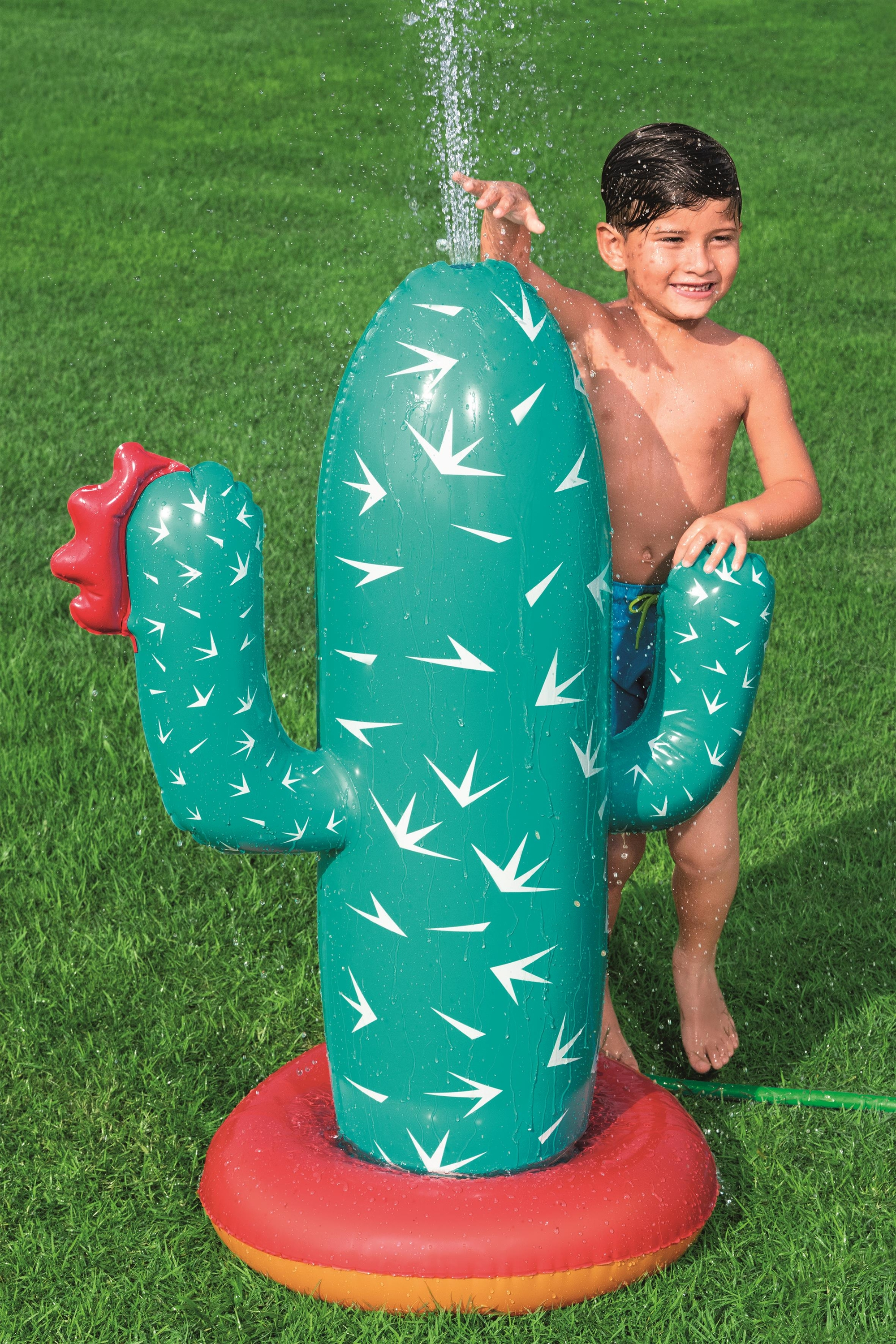 Dziecko bawi się nadmuchiwanym zraszaczem w kształcie kaktusa, woda pryska.