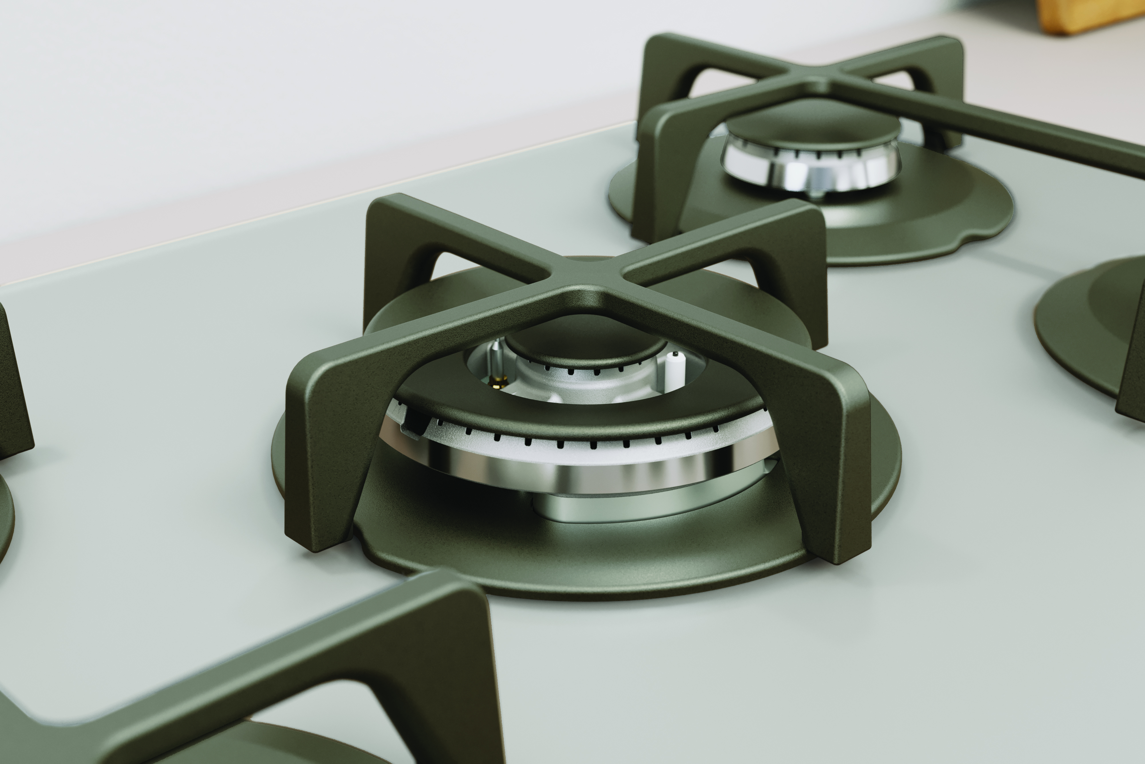 Zbliżenie palników kuchenki gazowej. Ciemnoszare palniki ze srebrnymi pierścieniami. Powierzchnia jest jasnoszara.