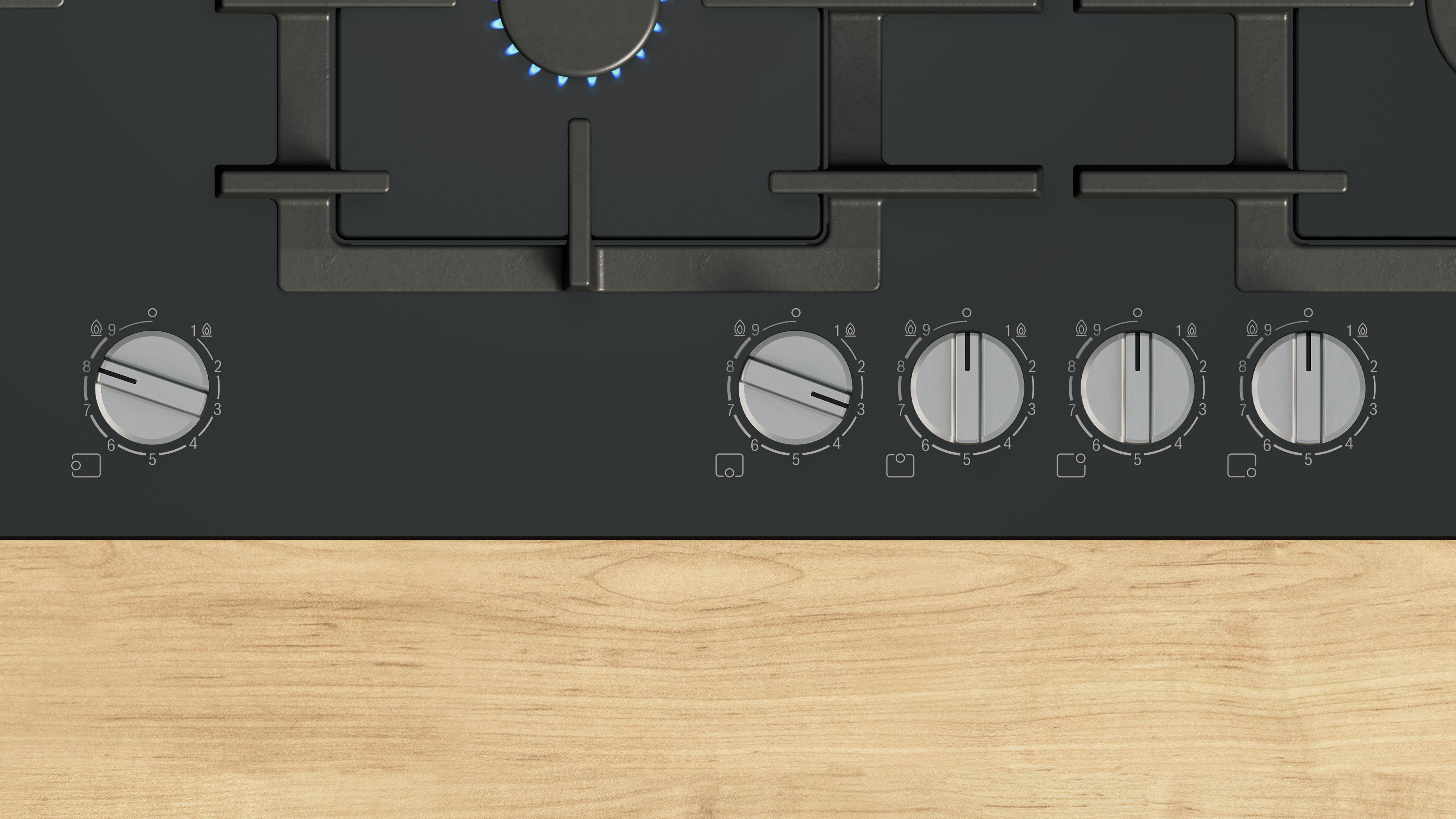 Zbliżenie czarnej płyty grzewczej z włączonymi palnikami gazowymi, pokrętłami i drewnianym blatem.