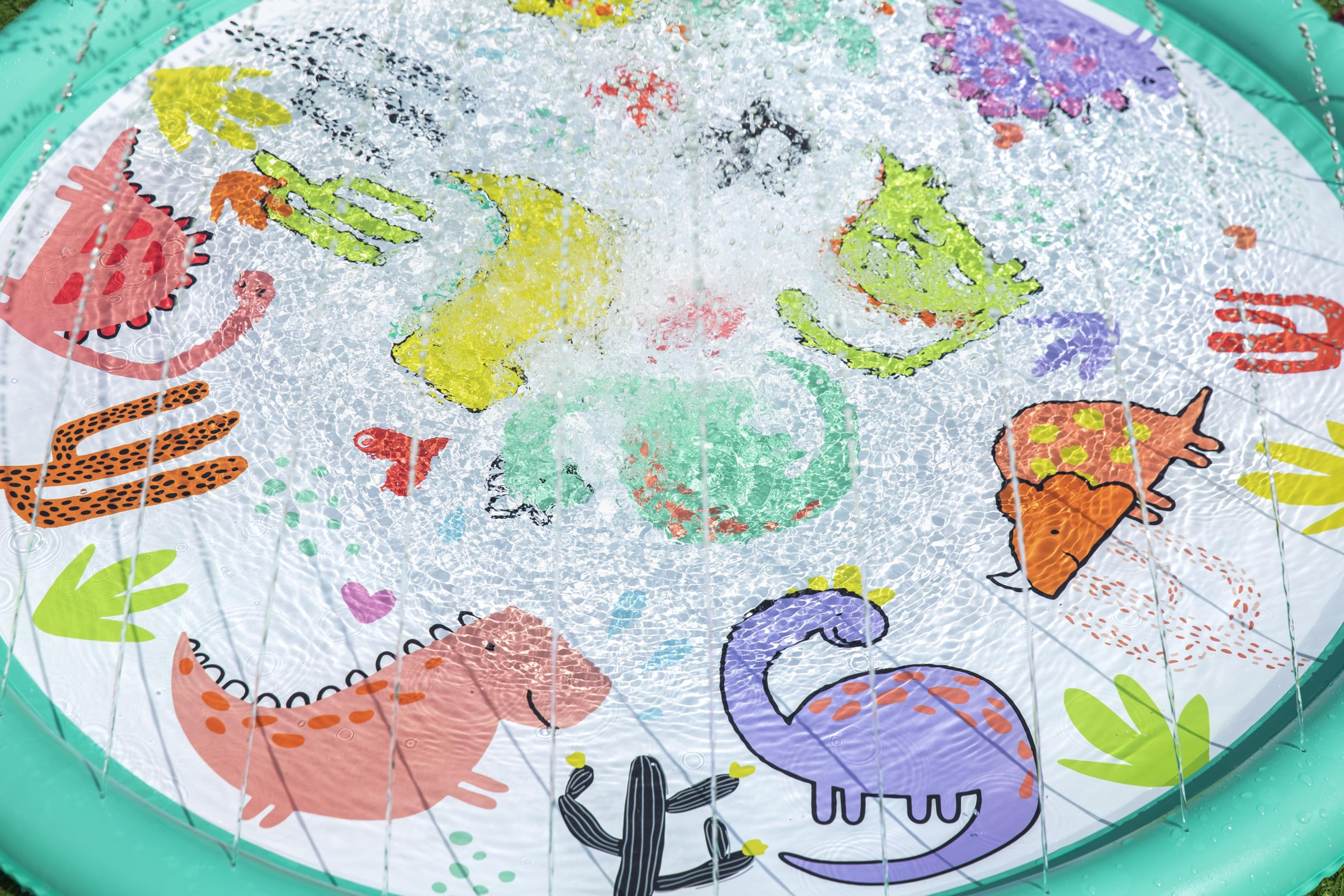 Piscina gonfiabile rotonda con spruzzi d'acqua, azzurra con disegni di dinosauri.