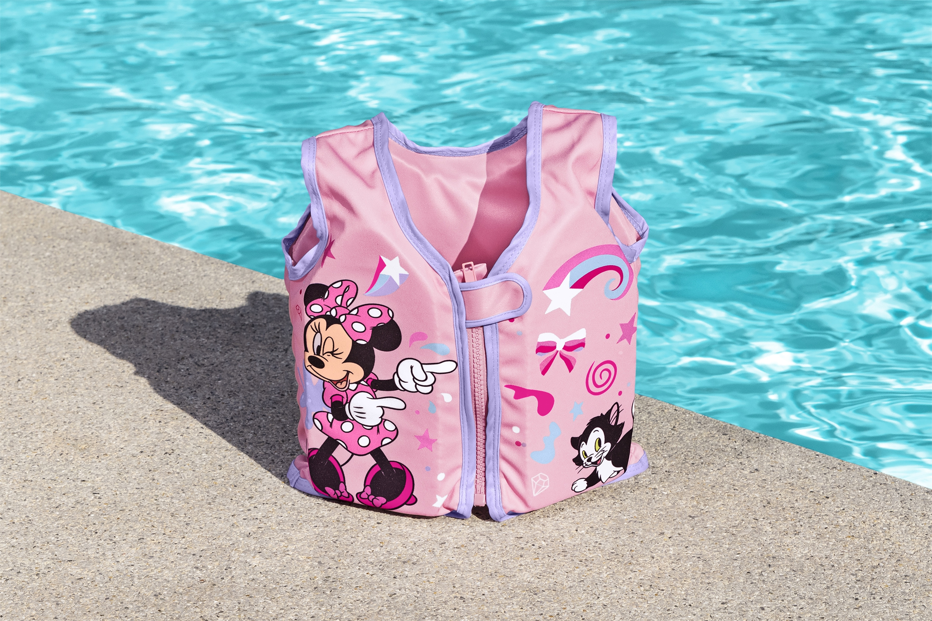 Gilet di salvataggio rosa di Minnie Mouse su una superficie vicino a una piscina.