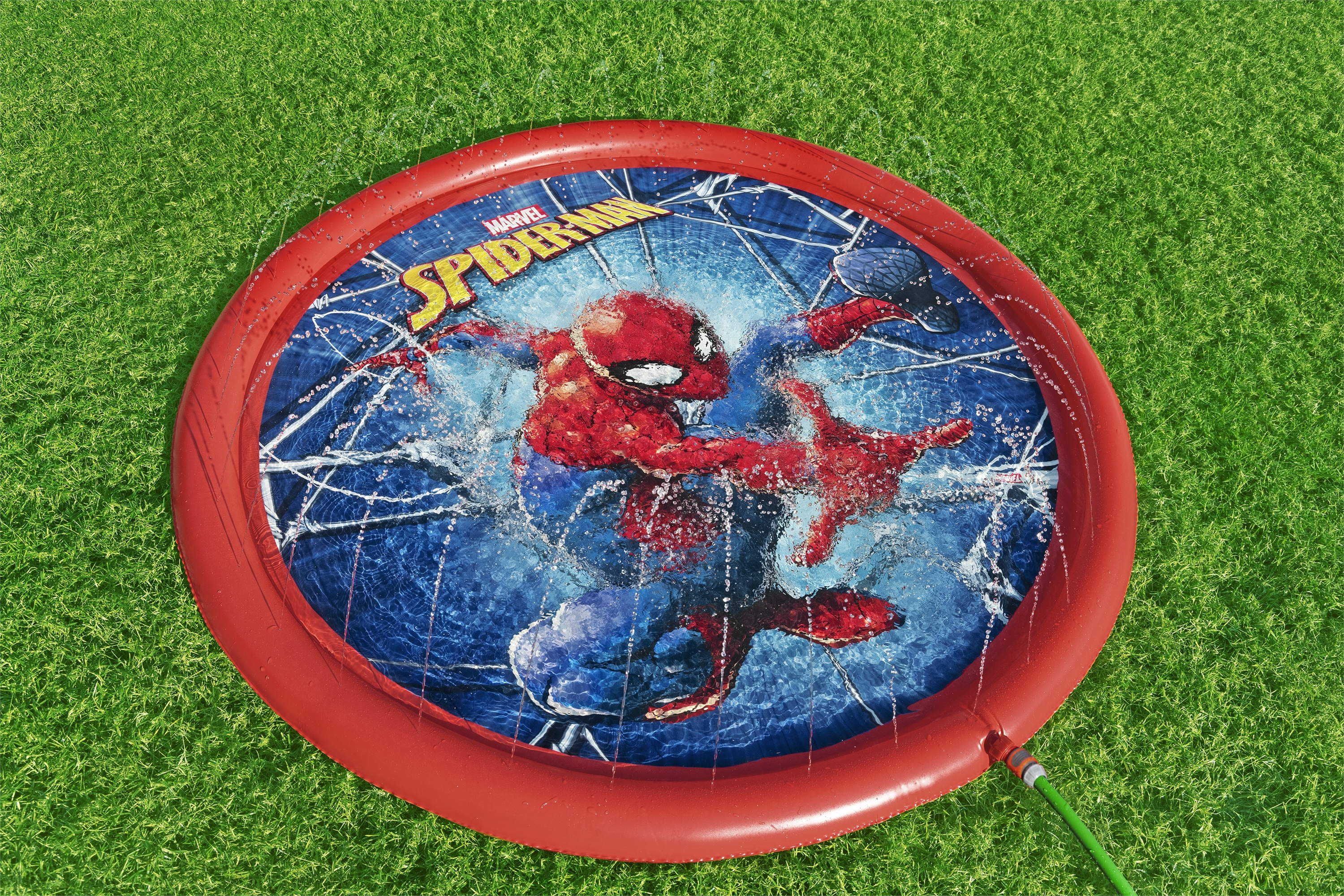Czerwony basen Spider-Man z rozpryskami wody. Zielona trawa w tle.