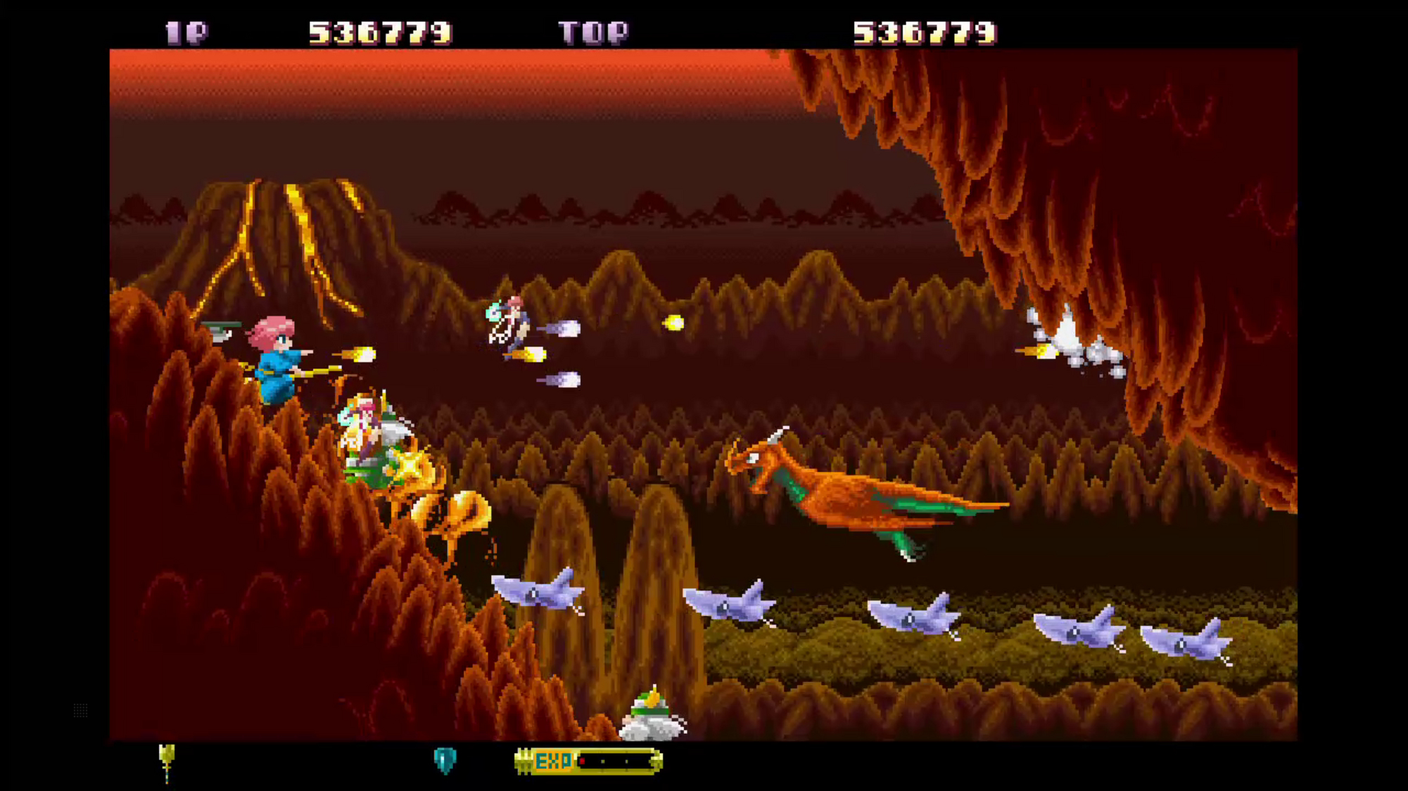 Scena gry w pikselach z postaciami, wrogami i tłem wulkanu. Wskaźniki wyniku i życia na górze.