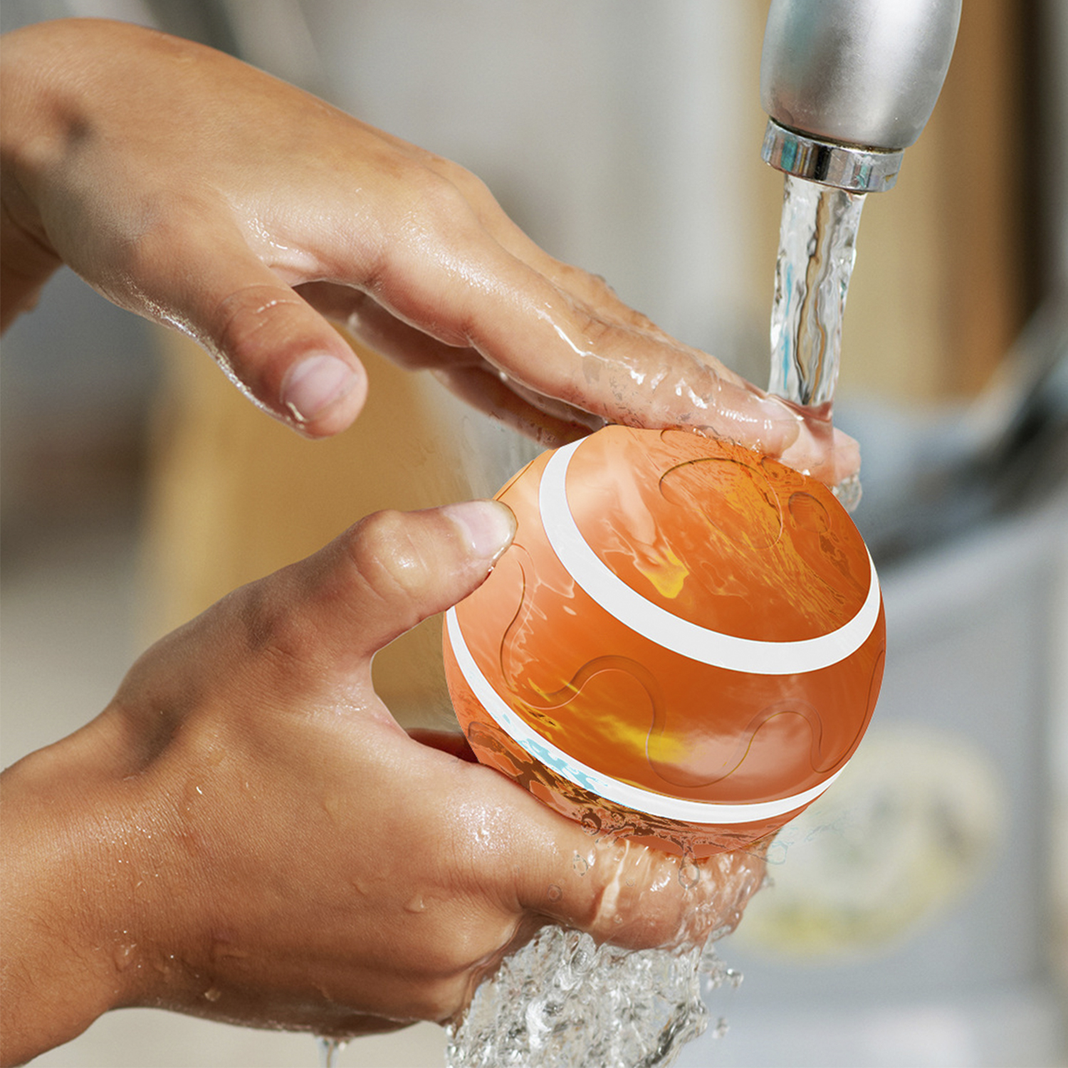 Mani che lavano una palla giocattolo arancione sotto l'acqua corrente. Strisce bianche sono visibili sulla palla.