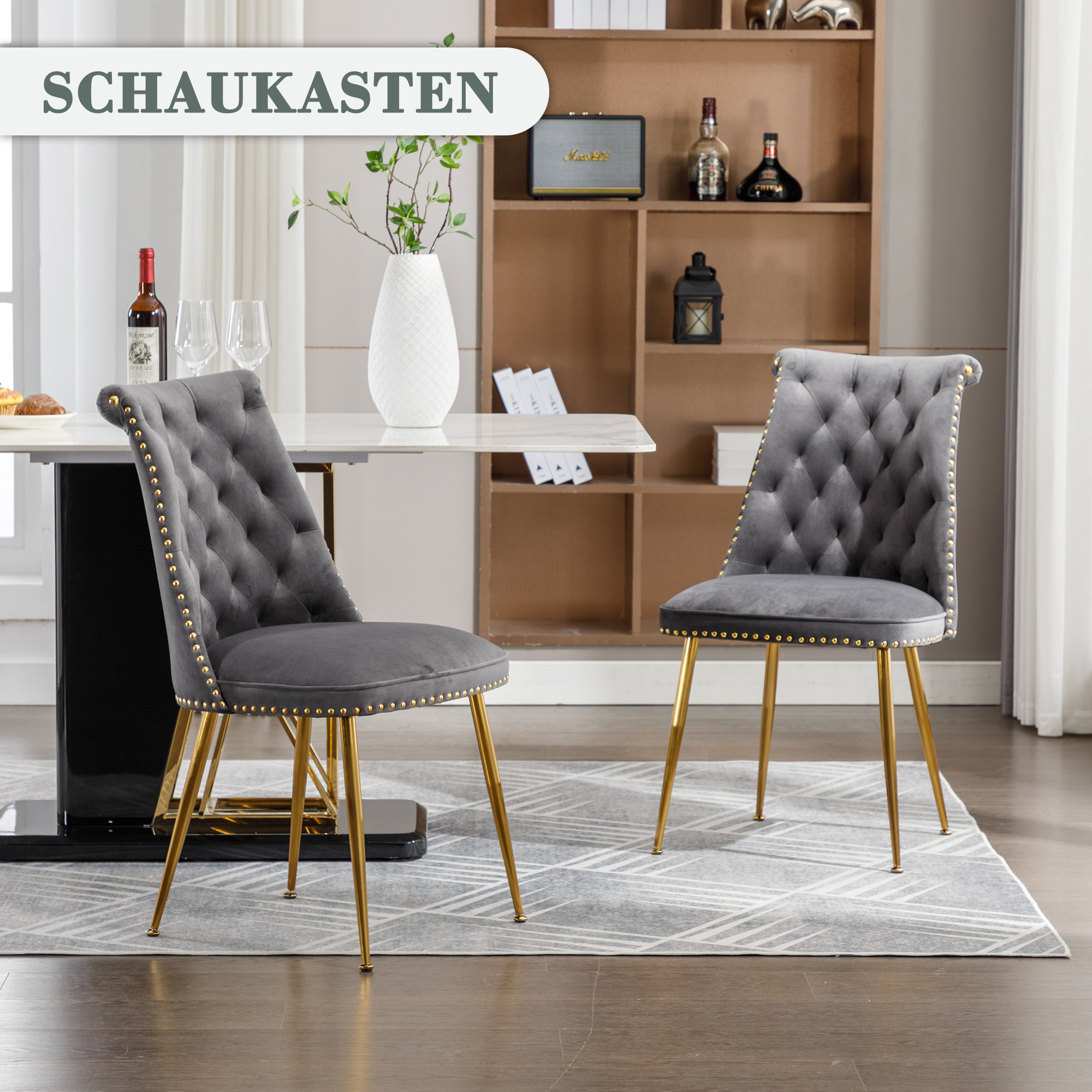 Ein Esszimmer mit zwei grauen Stühlen mit goldenen Beinen und einem weißen Tisch.