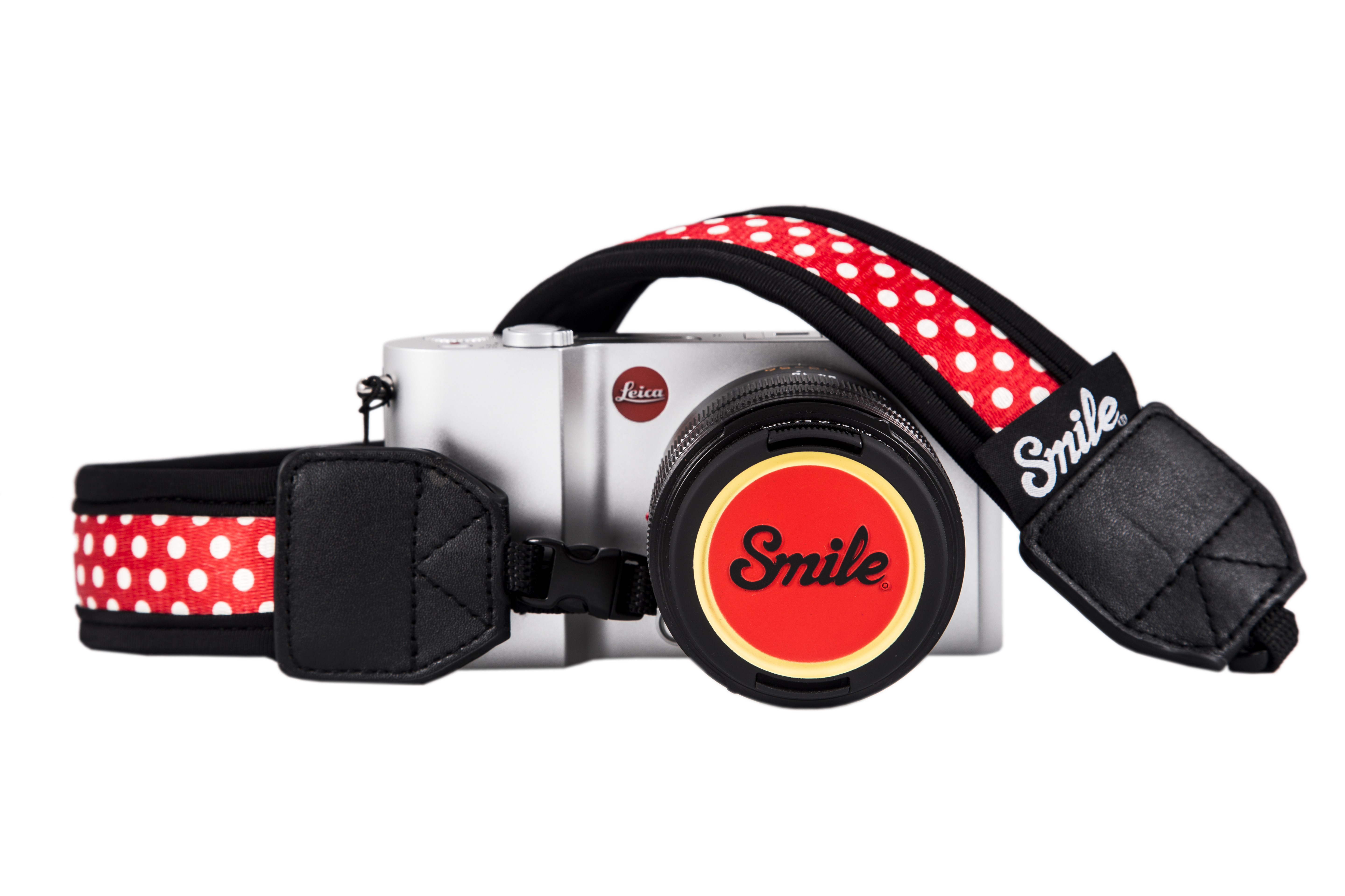 Fotocamera con cinturino a pois rossi e tappo rosso con la scritta 'Smile'.