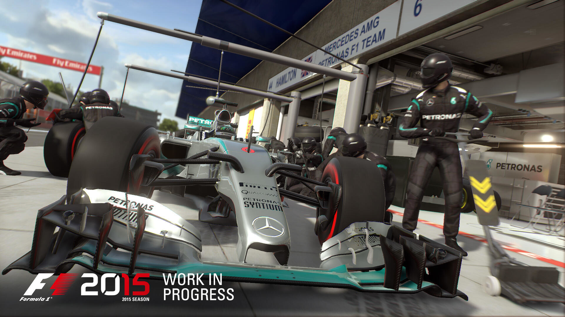 Okładka gry F1 2015. Samochód Formuły 1 naprawiany przez zespół podczas pit stopu.