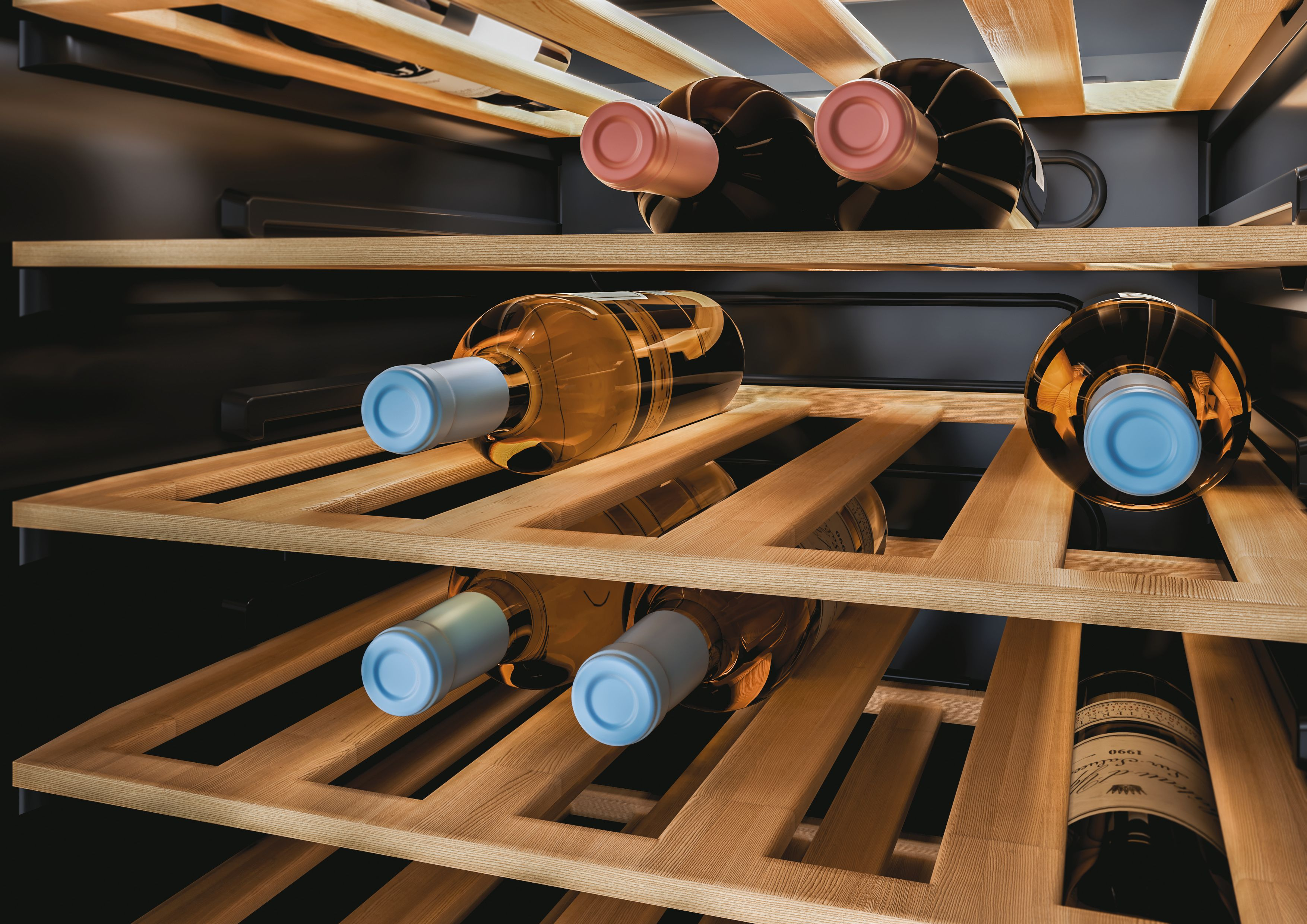 Bottiglie di vino all'interno di una cantinetta. Ripiani in legno e interni scuri. Le bottiglie sono illuminate.