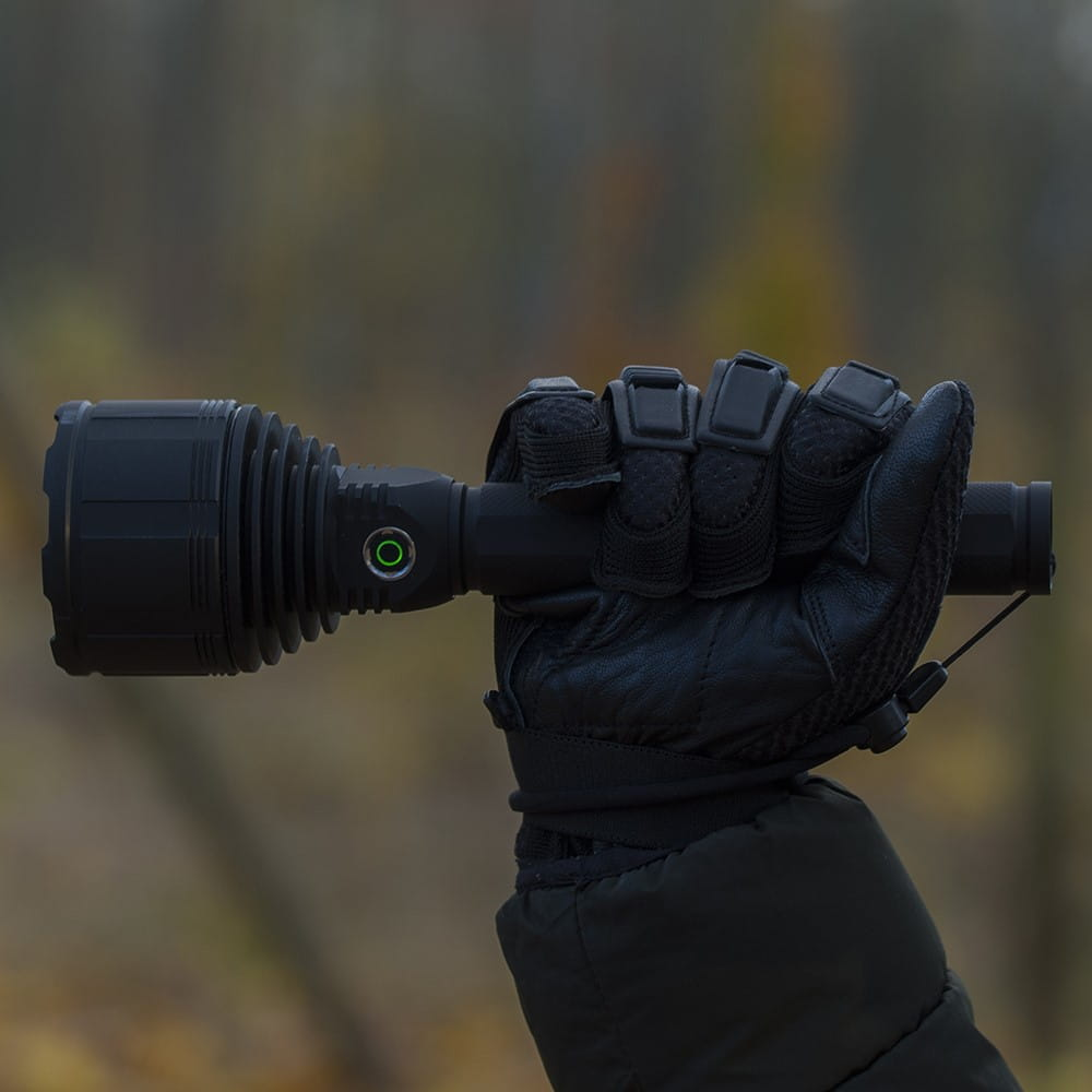 Dłoń w czarnej rękawicy trzymająca czarną latarkę.