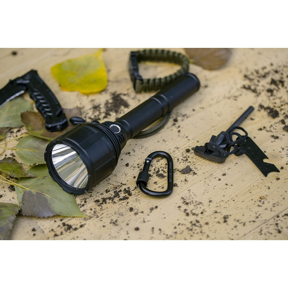 Czarna latarka z innymi przedmiotami na drewnianej powierzchni.