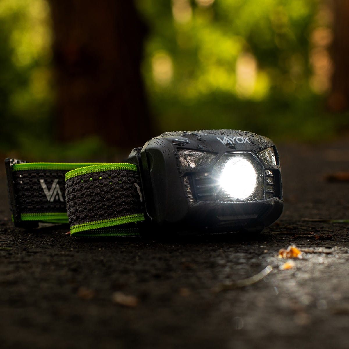 Czarna latarka czołowa Vayox na ciemnej ścieżce. Światło jest włączone, oświetlając ścieżkę.