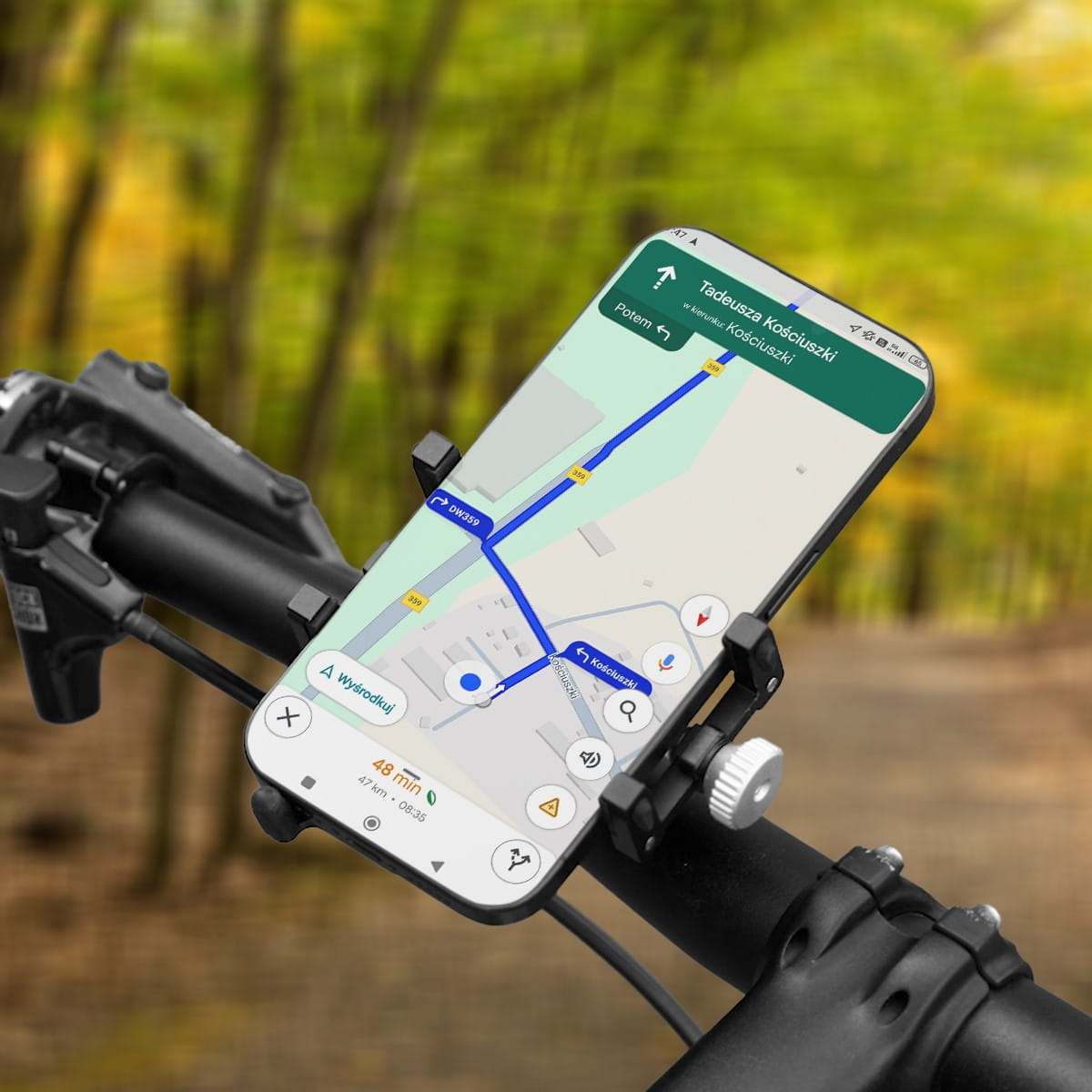 Telefon na kierownicy roweru pokazujący mapę. Jest słoneczny dzień, a tło to rozmyte drzewa.
