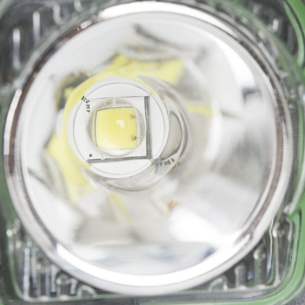 Zbliżenie reflektora rowerowego. Światło jest włączone, a soczewka jest przezroczysta.