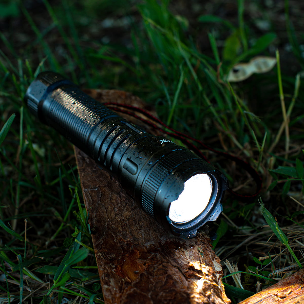 Czarna latarka na drewnianej powierzchni, oświetlająca obszar.