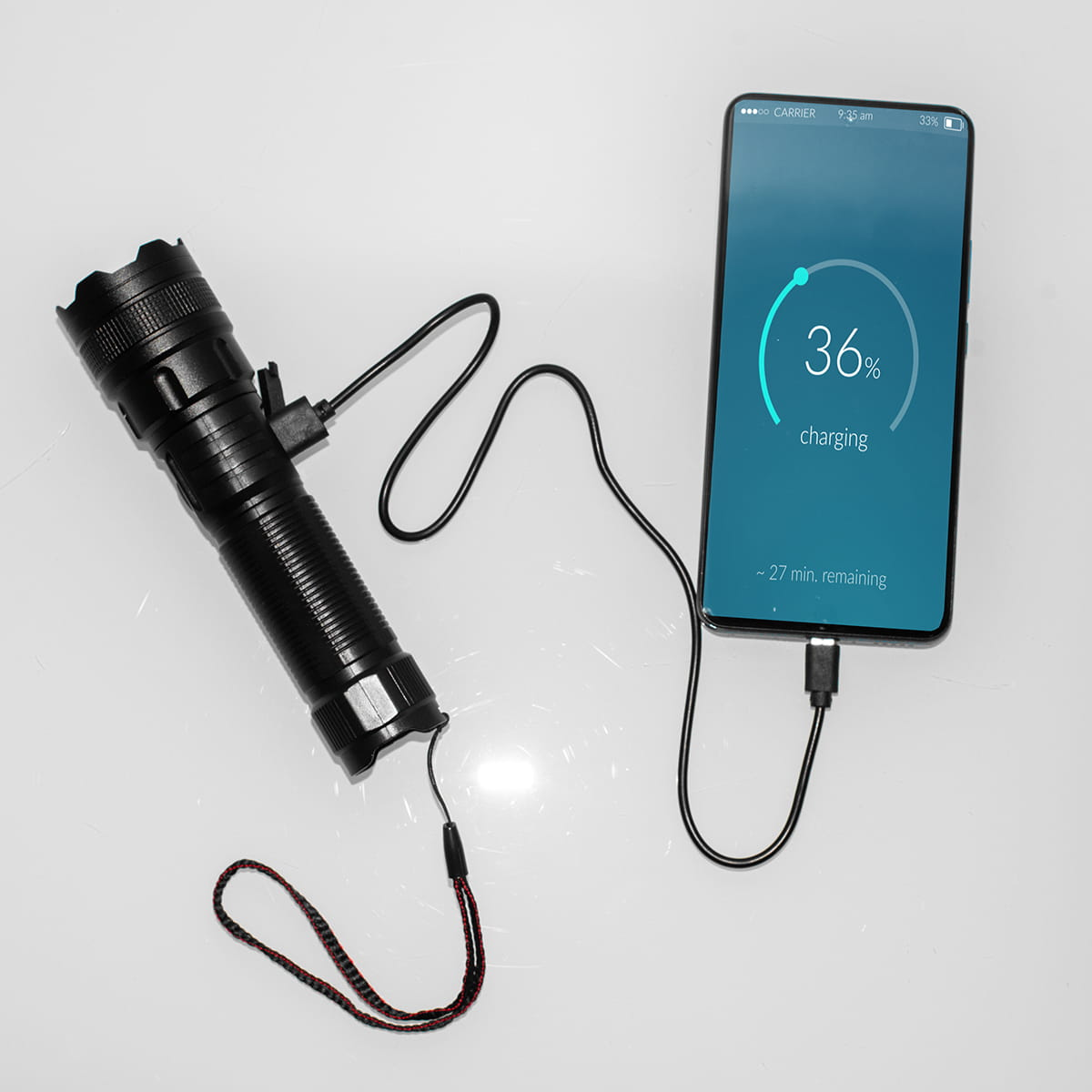Czarna latarka podłączona do telefonu, ładująca się w 36%.