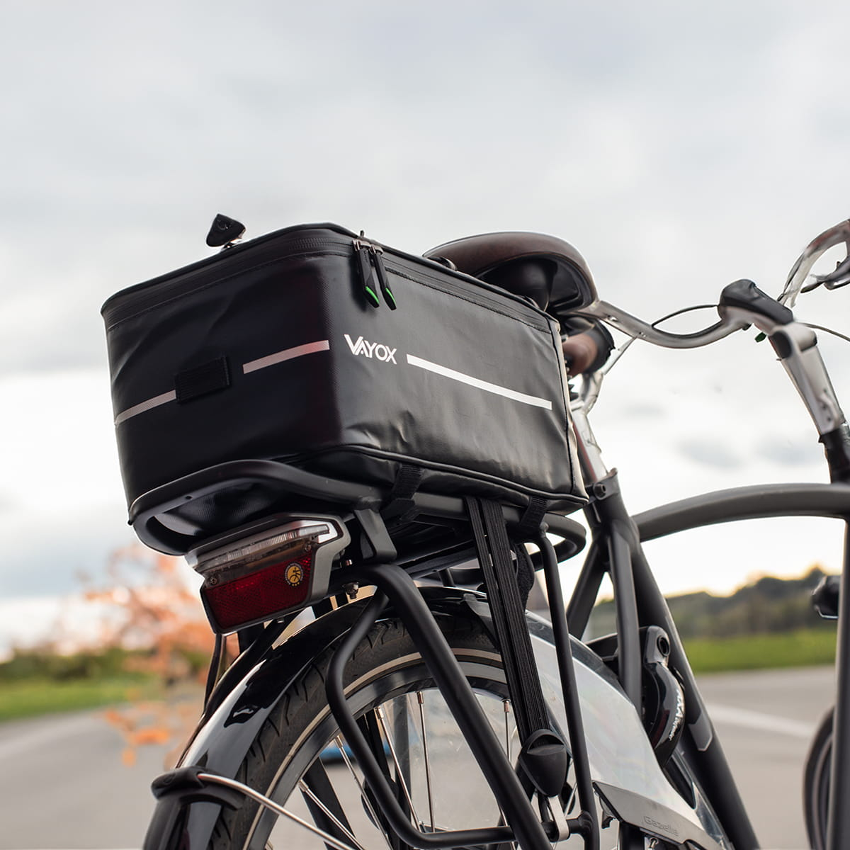 Czarny rower z czarną torbą Vayox z tyłu, na drodze. Niebo jest pochmurne.