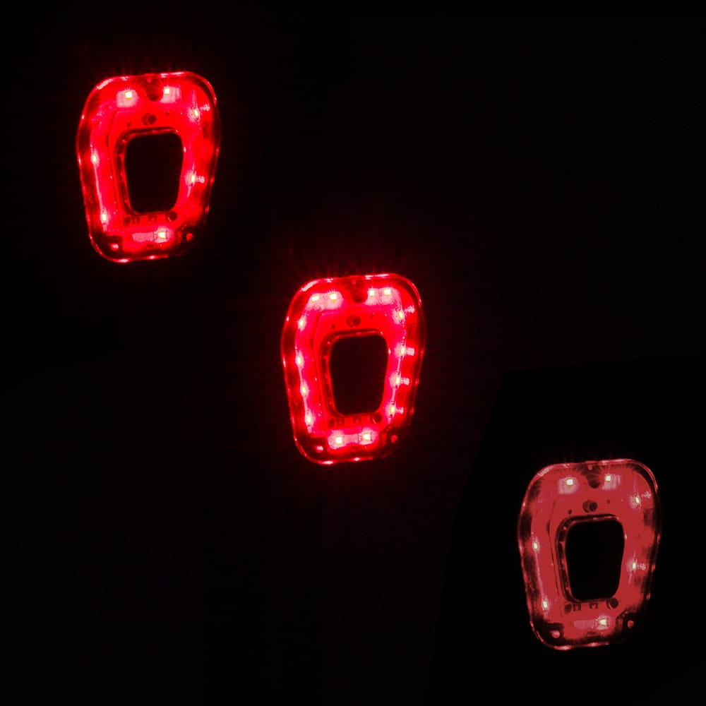 Trzy świecące czerwone światła, prostokątne z otworem pośrodku, na czarnym tle.