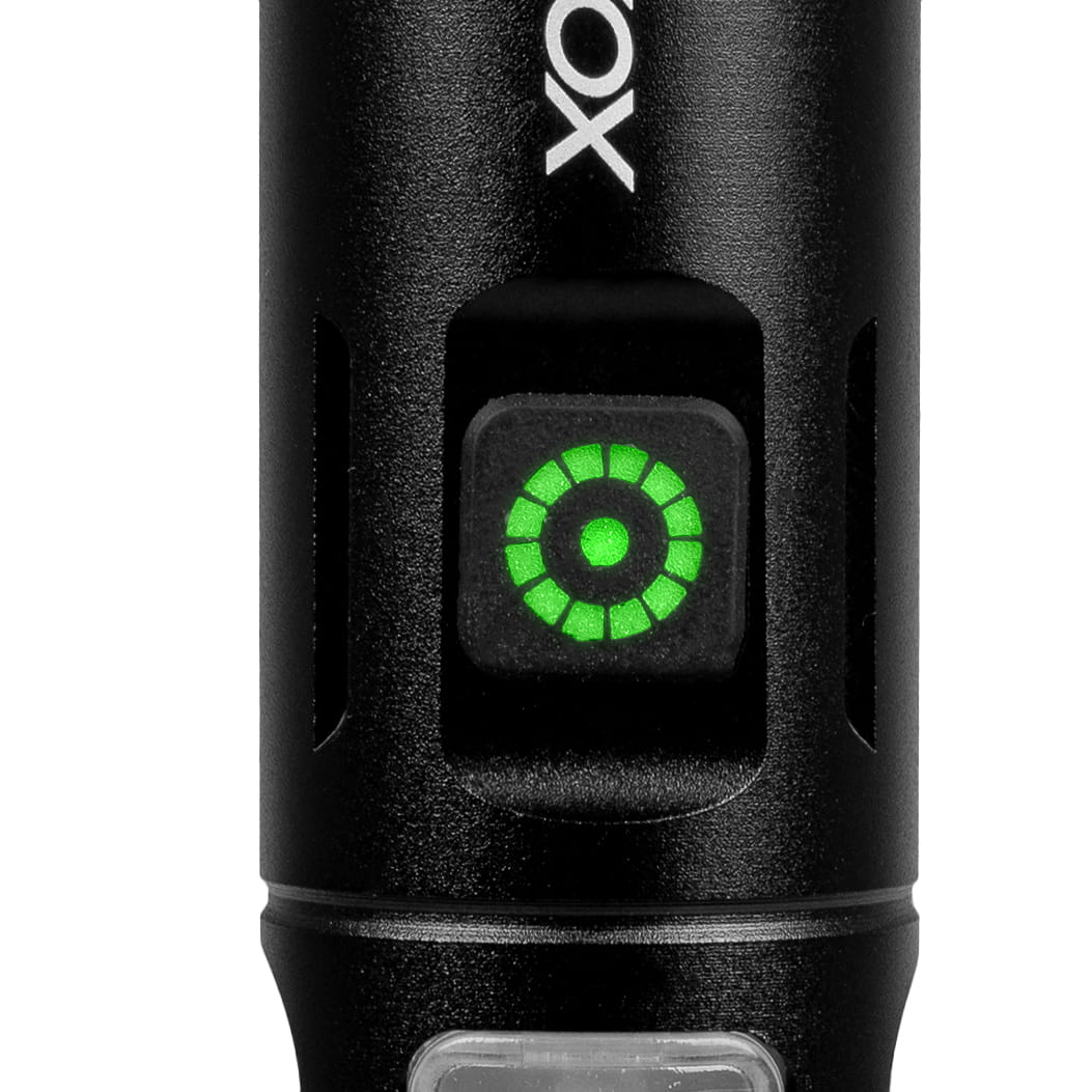 Zbliżenie czarnego przycisku latarki. Przycisk jest zielony i ma okrągły wzór.