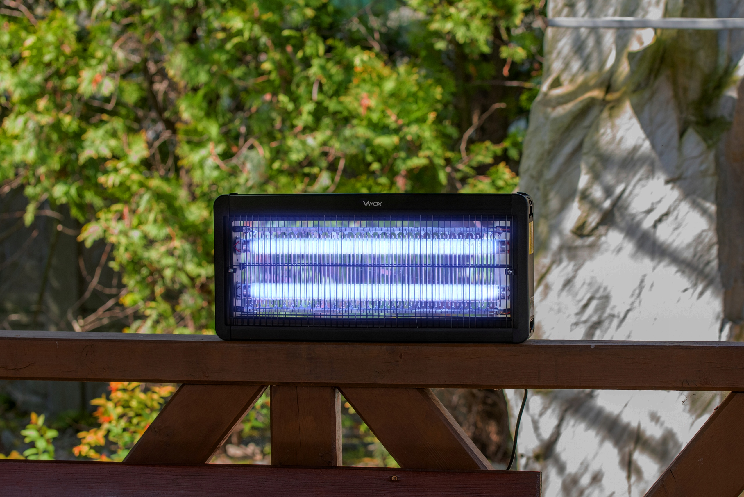 Czarny zabijacz owadów na drewnianym pokładzie, z niebieskim światłem emitowanym z wnętrza.