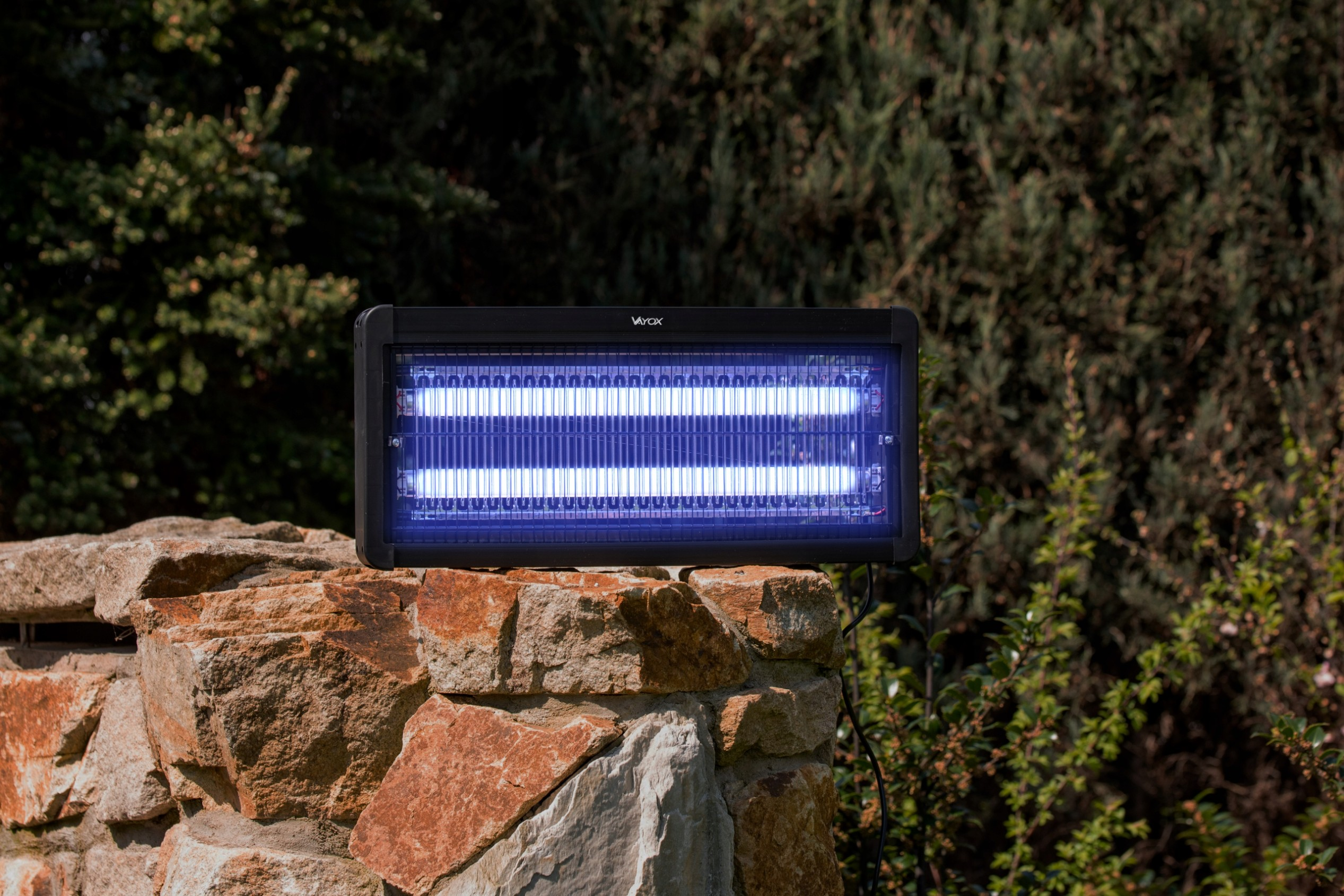 Czarny zabijacz owadów na kamiennej ścianie. Widoczne niebieskie światło z wnętrza.