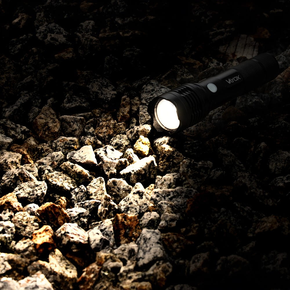 Czarna latarka świecąca na skały. Ciemne tło.