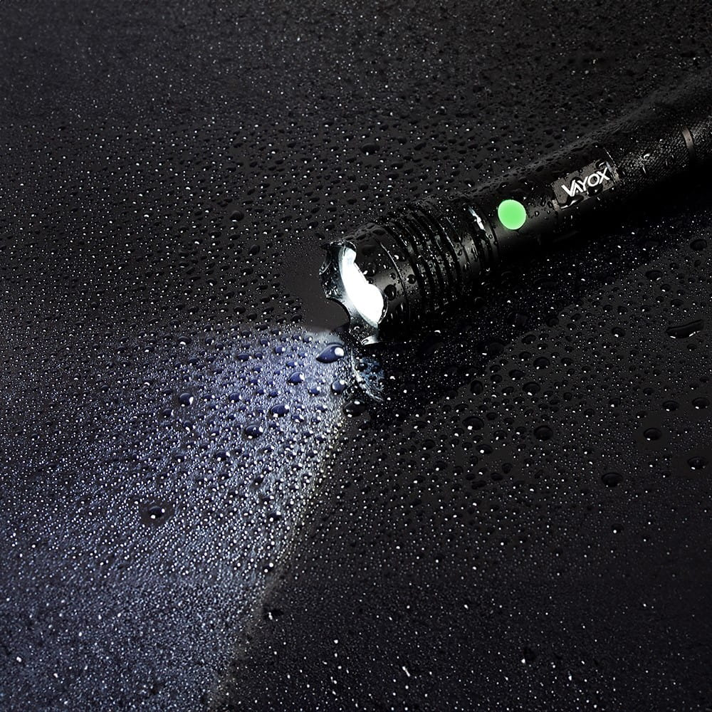 Latarka świeci na krople wody. Woda odbija światło.