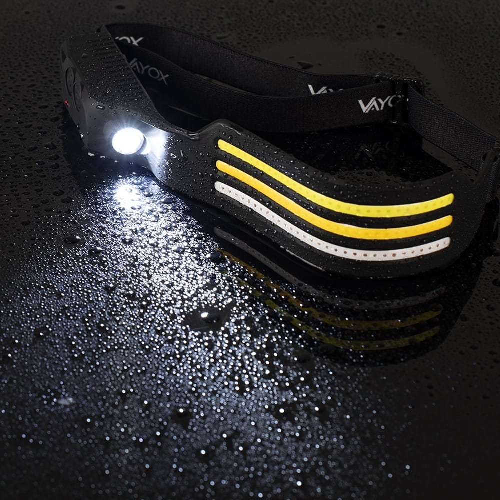 Latarka czołowa z wieloma światłami i kroplami wody na czarnej powierzchni.