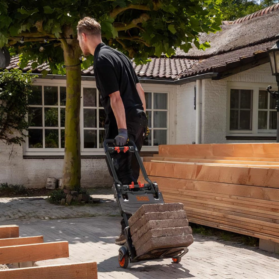 A man is pushing a cart with bricks and wood.
