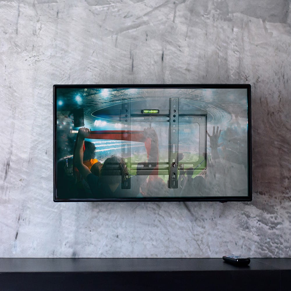 Telewizor zamontowany na ścianie z uchwytem, pokazujący tłum na stadionie.