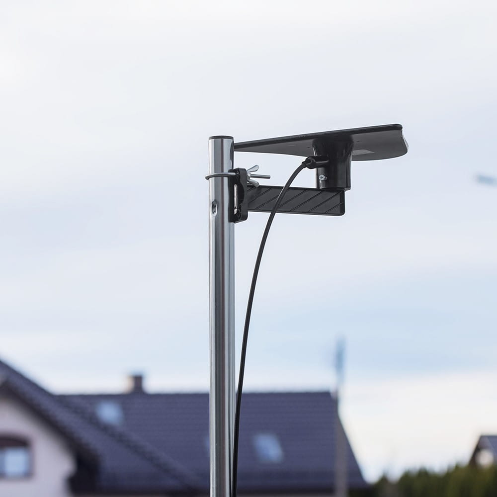 Czarna antena TV na metalowym słupie. Antena jest trójkątna. W tle zachmurzone niebo.