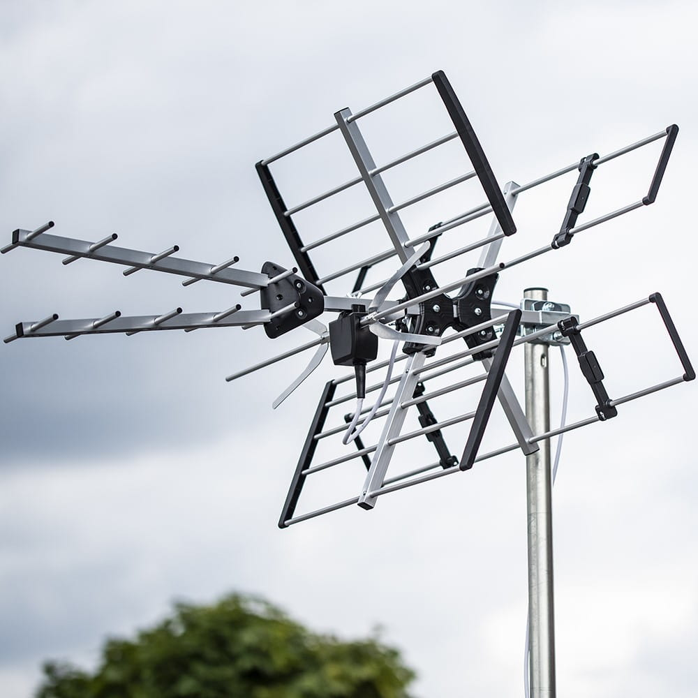 Antena telewizyjna zamontowana na zewnątrz. Antena jest srebrna i czarna, z pochmurnym niebem w tle.