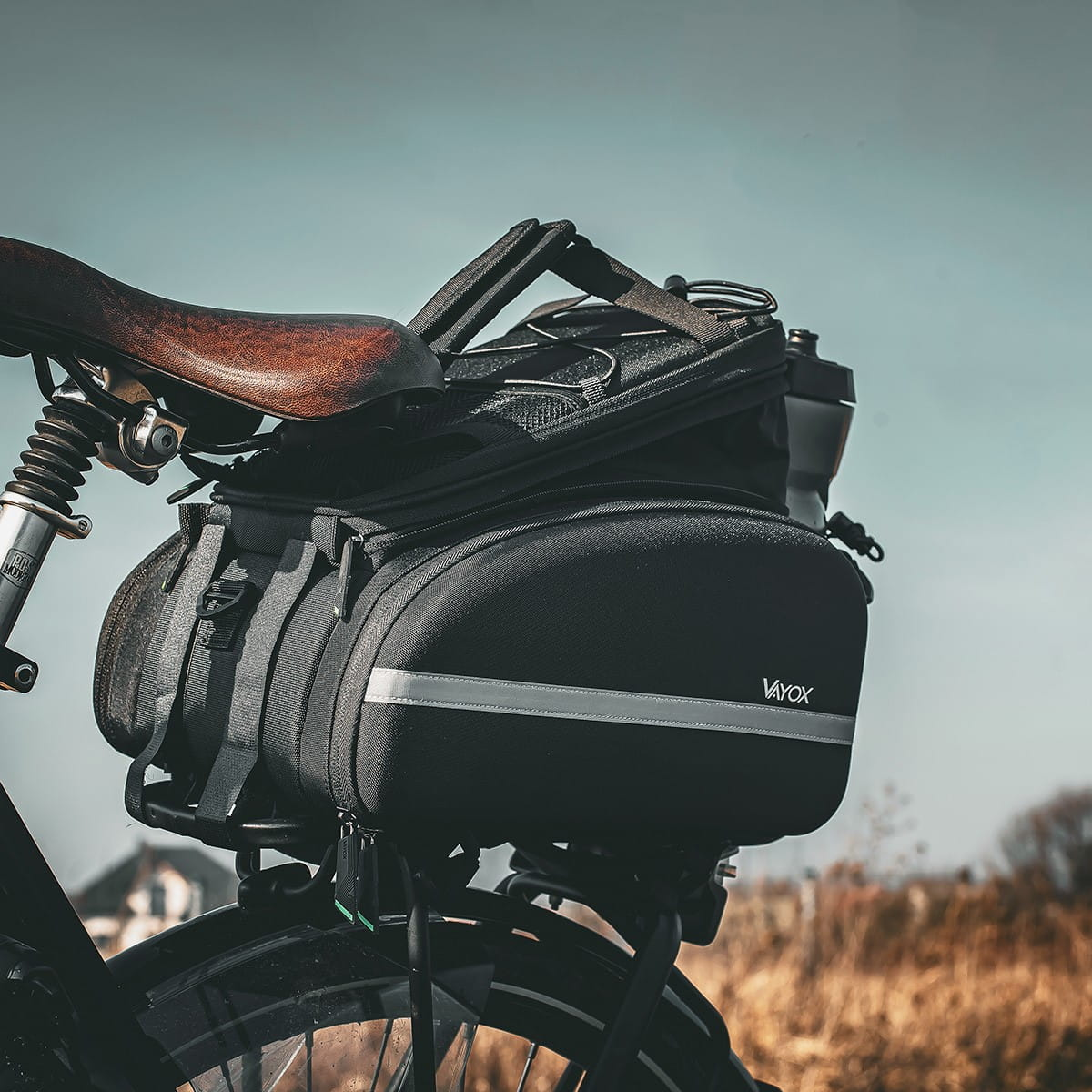 Czarna torba rowerowa zamontowana na rowerze. Torba ma odblaskowy pasek i uchwyt na bidon.