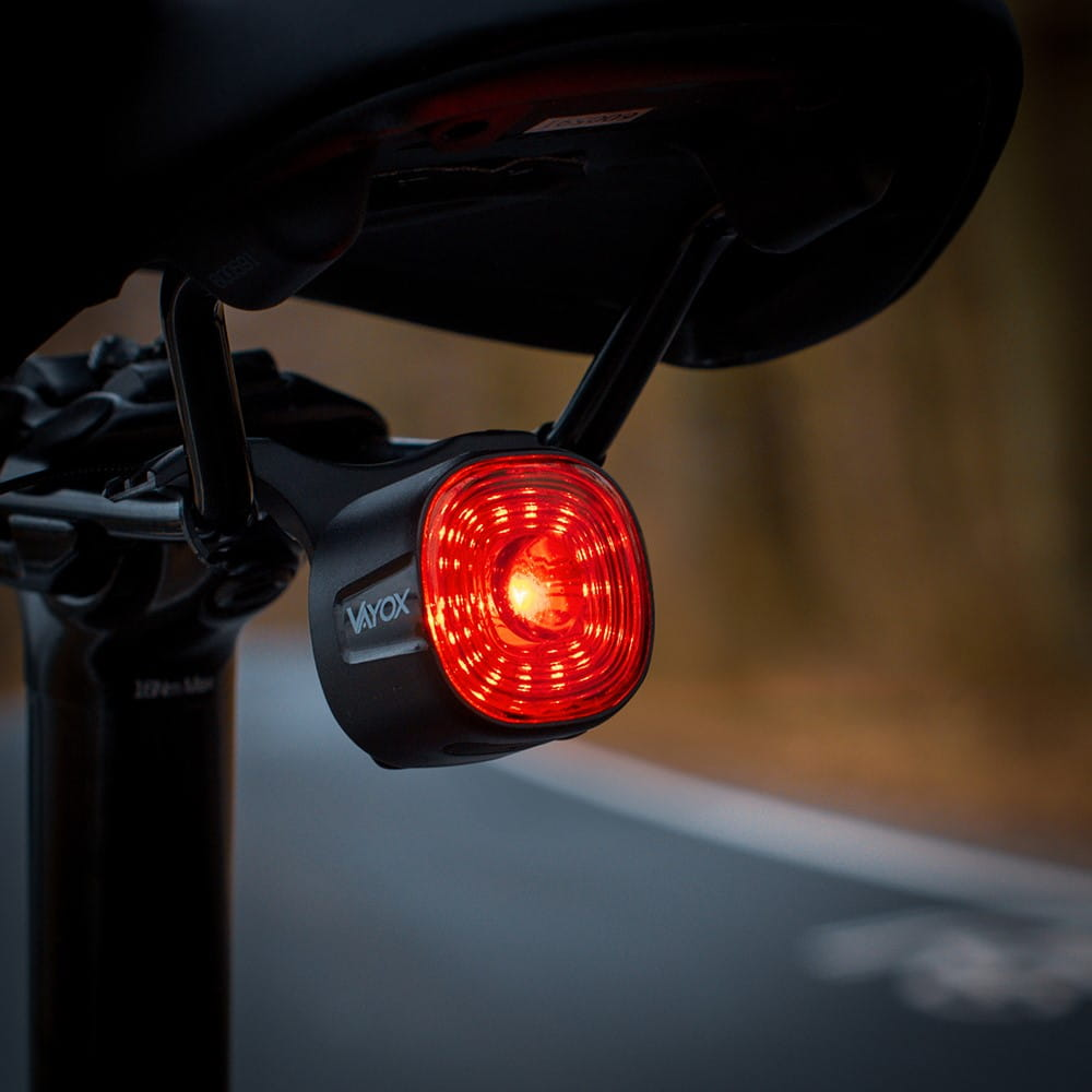 Czarne światło tylne roweru, świecące czerwone światło. Zamontowane na sztycy, rozmyte tło.