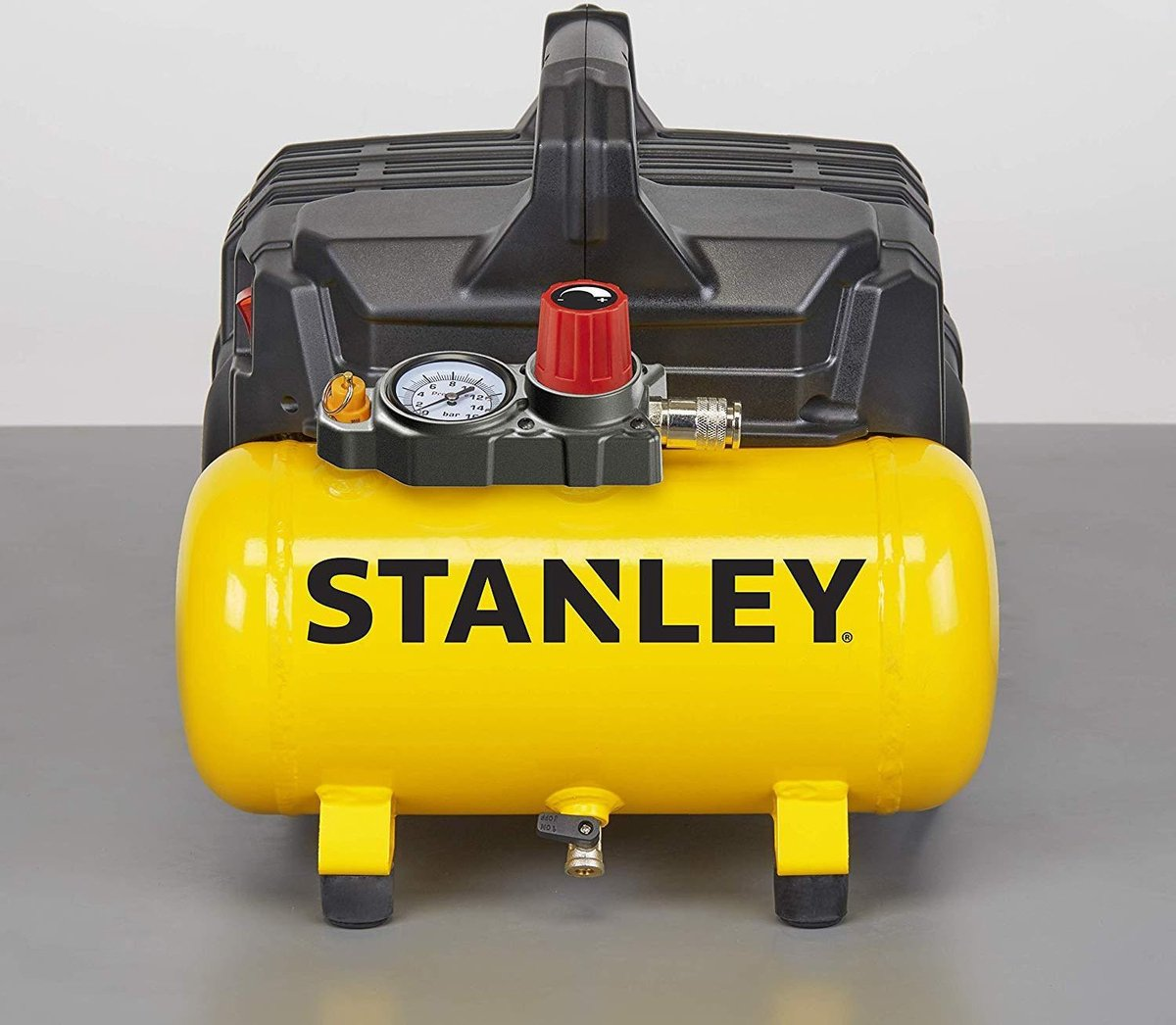 Close-up van een geel-zwarte Stanley luchtcompressor met een meter en handvat. De doos is open.
