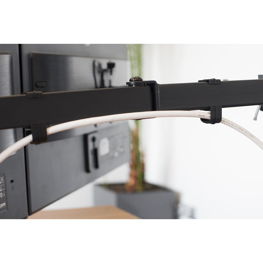 Zbliżenie czarnego uchwytu do monitora. Biały kabel jest przymocowany do monitora.