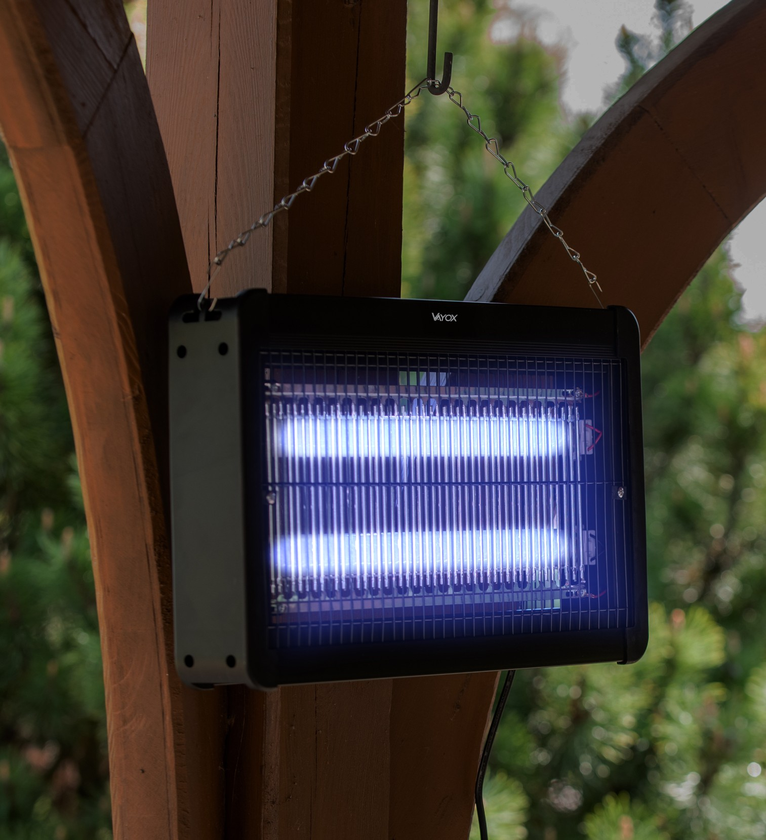 Czarny zabijacz owadów wiszący na drewnianej konstrukcji. Emituje niebieskie światło.