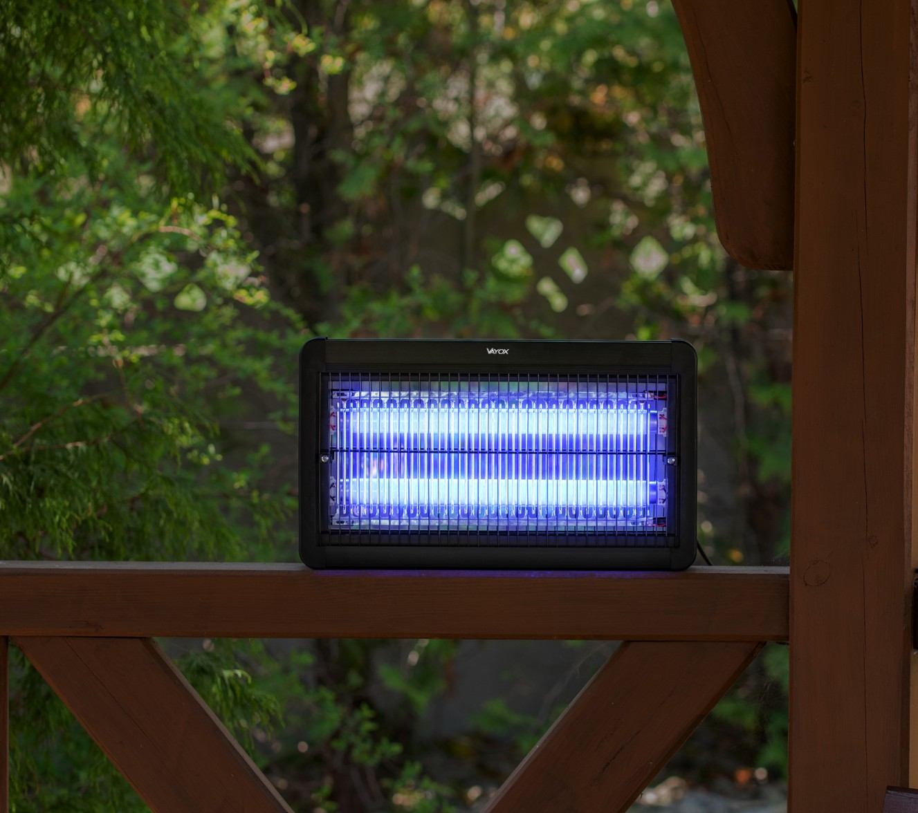 Zabijacz owadów na drewnianym ganku, z niebieskim światłem UV. Widoczne zielone liście.