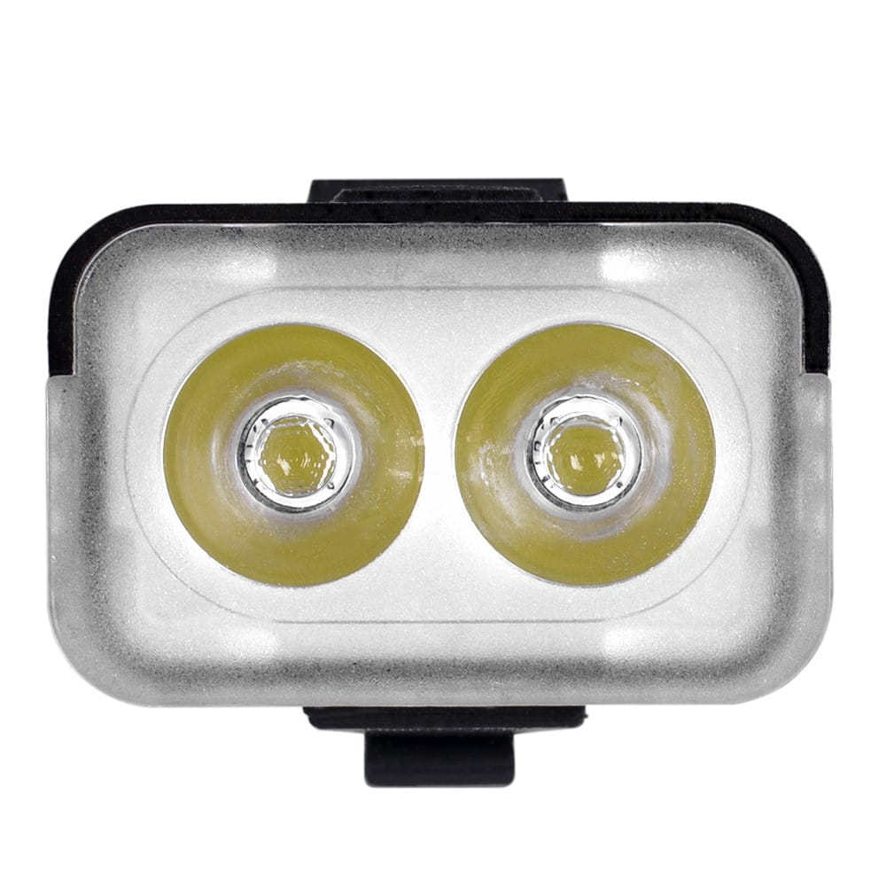 Lampa rowerowa z dwiema soczewkami. Srebrna rama. Emitowane żółte światło. Czarny uchwyt.