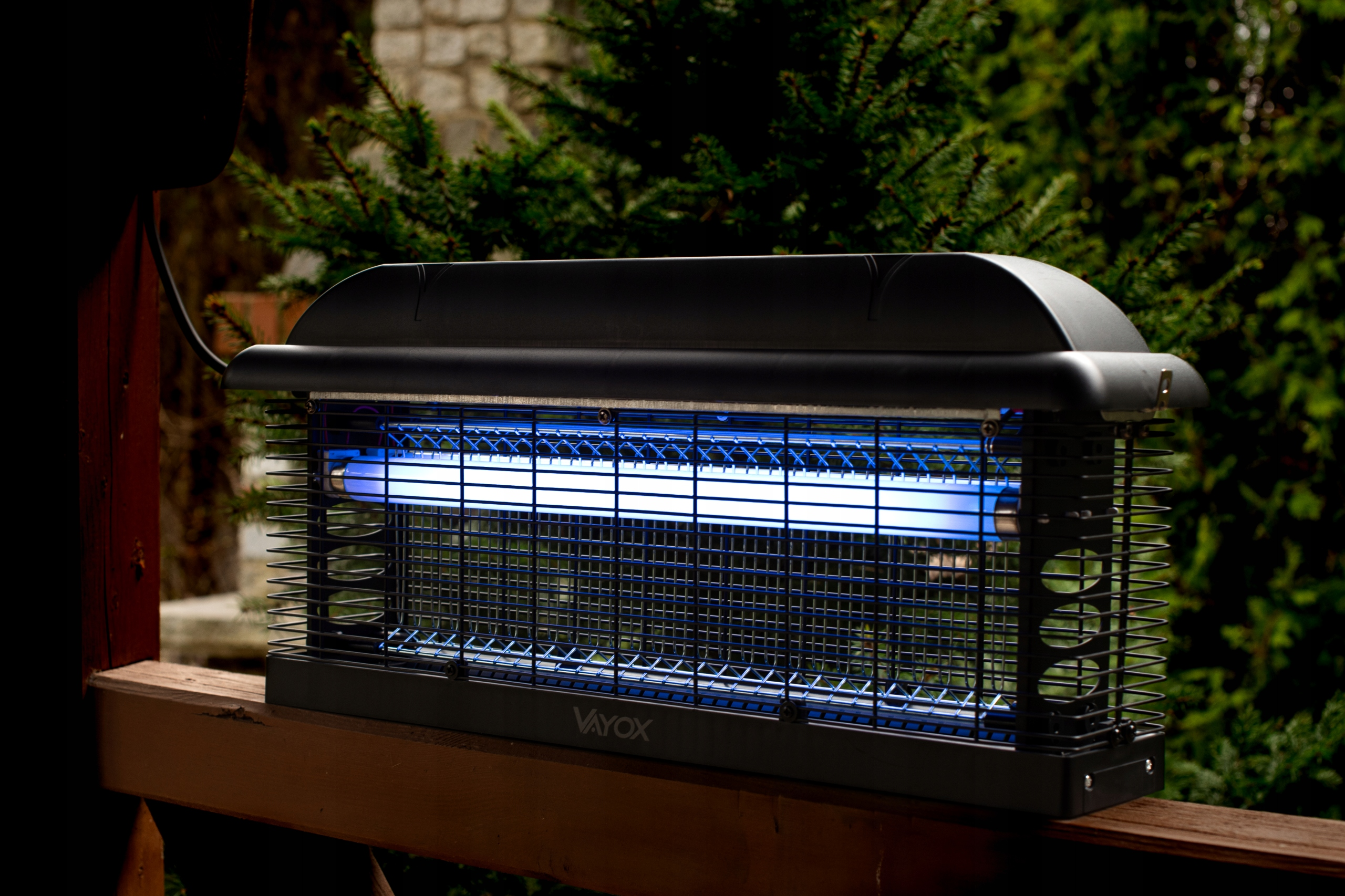 Czarny zabijacz owadów na drewnianej powierzchni z zielonym tłem. Zabijacz ma niebieskie światła.