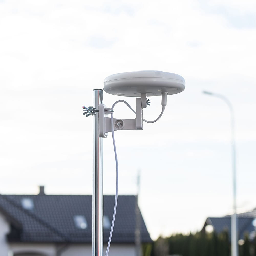 Biała antena przymocowana do metalowego słupa. Na tle widoczne niebo.