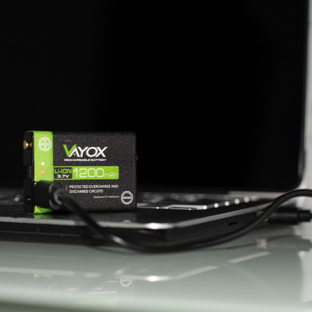 Czarny akumulator ładujący się na laptopie, zielone połączenie kablowe.