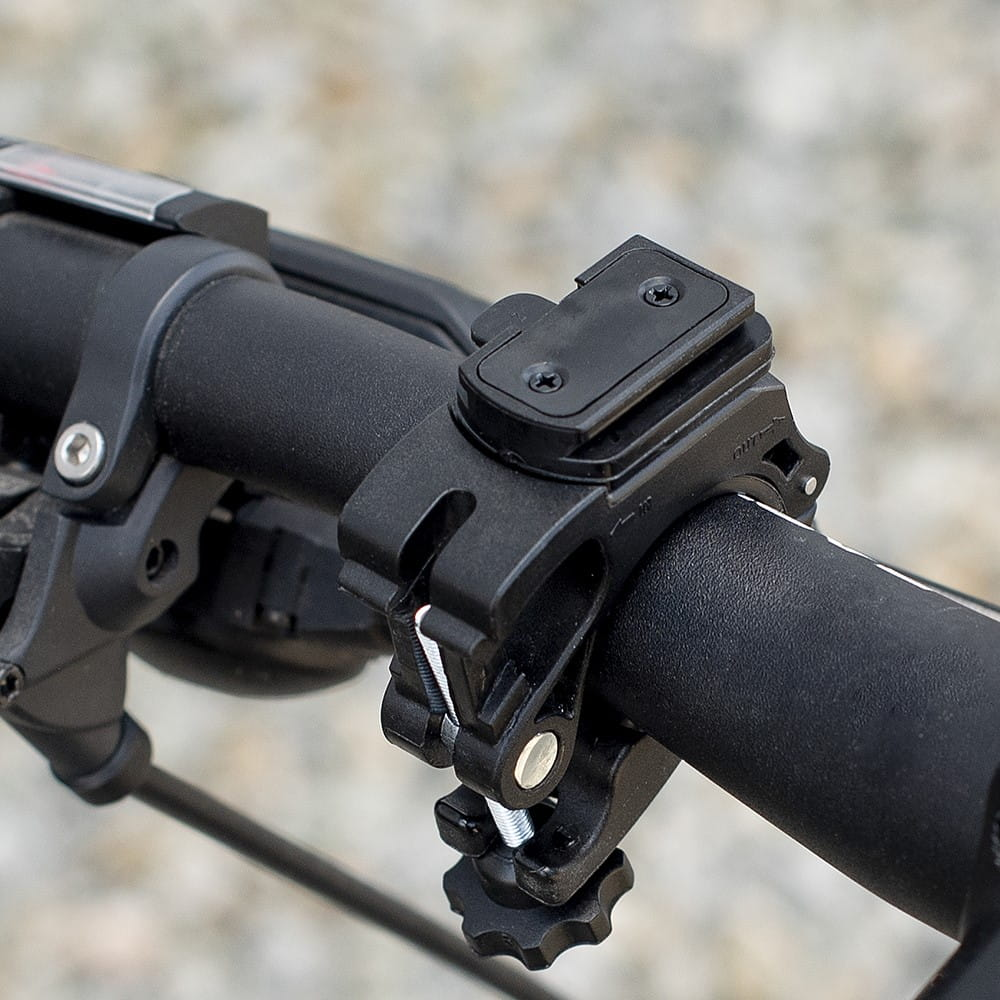 Czarny uchwyt rowerowy na kierownicy, zbliżenie. Srebrna śruba i pokrętło regulacji.